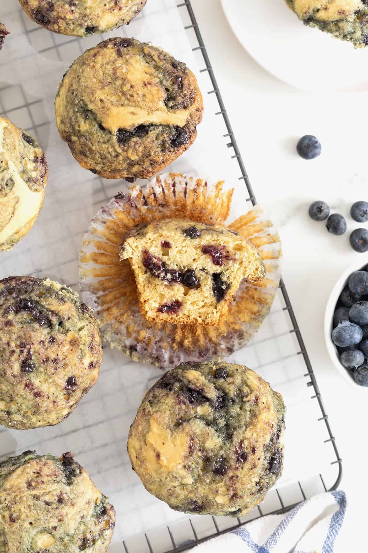 Six blueberry swirl muffins on a wire cooling rack.