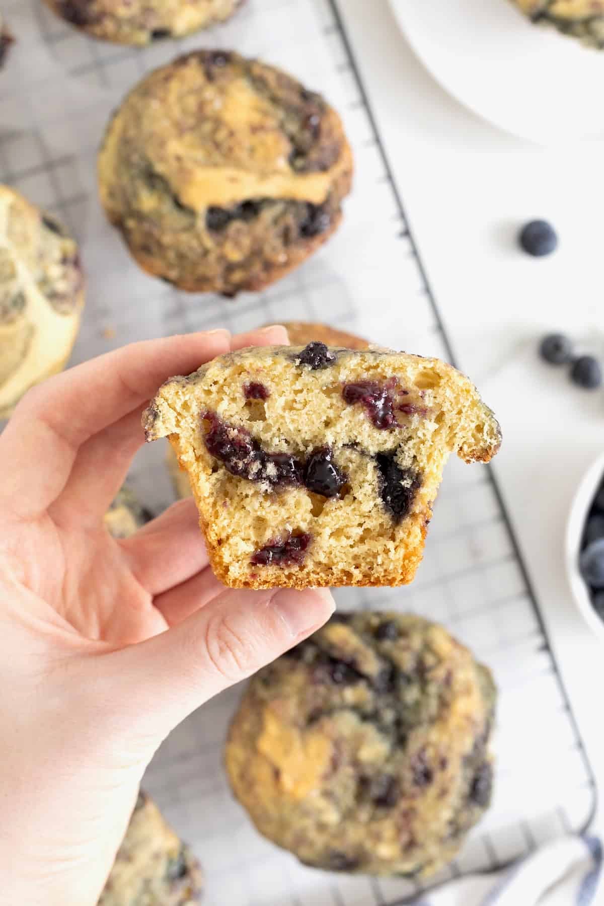 A hand holding a blueberry swirl muffin cut in half.