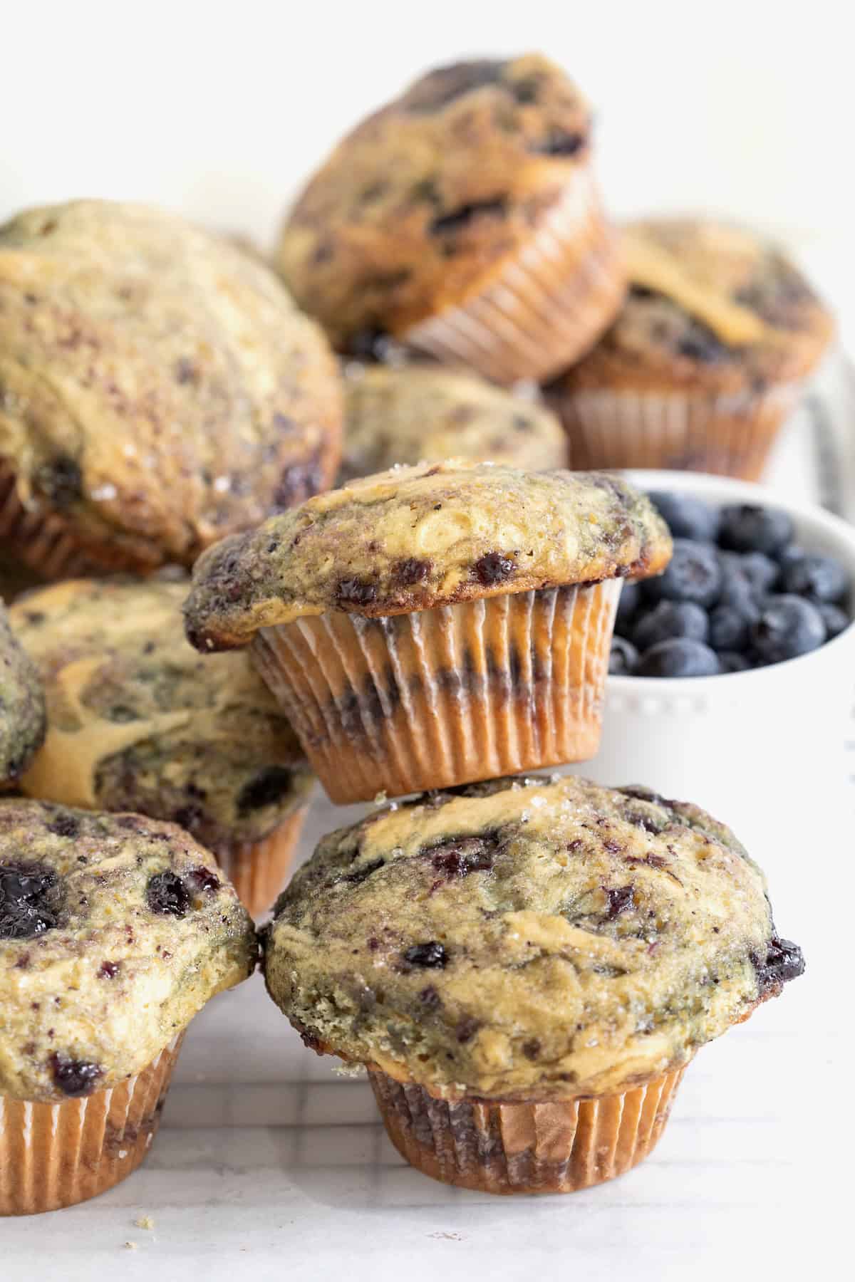 Piles of blueberry swirl muffins on a white surface.