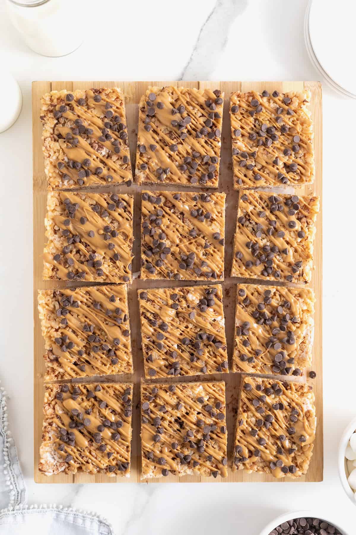 Peanut butter chocolate chip Rice Krispies treats cut into squares on a wooden cutting board.