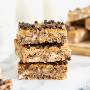 A stack of three peanut butter chocolate chip Rice Krispies treats on a white marble counter.