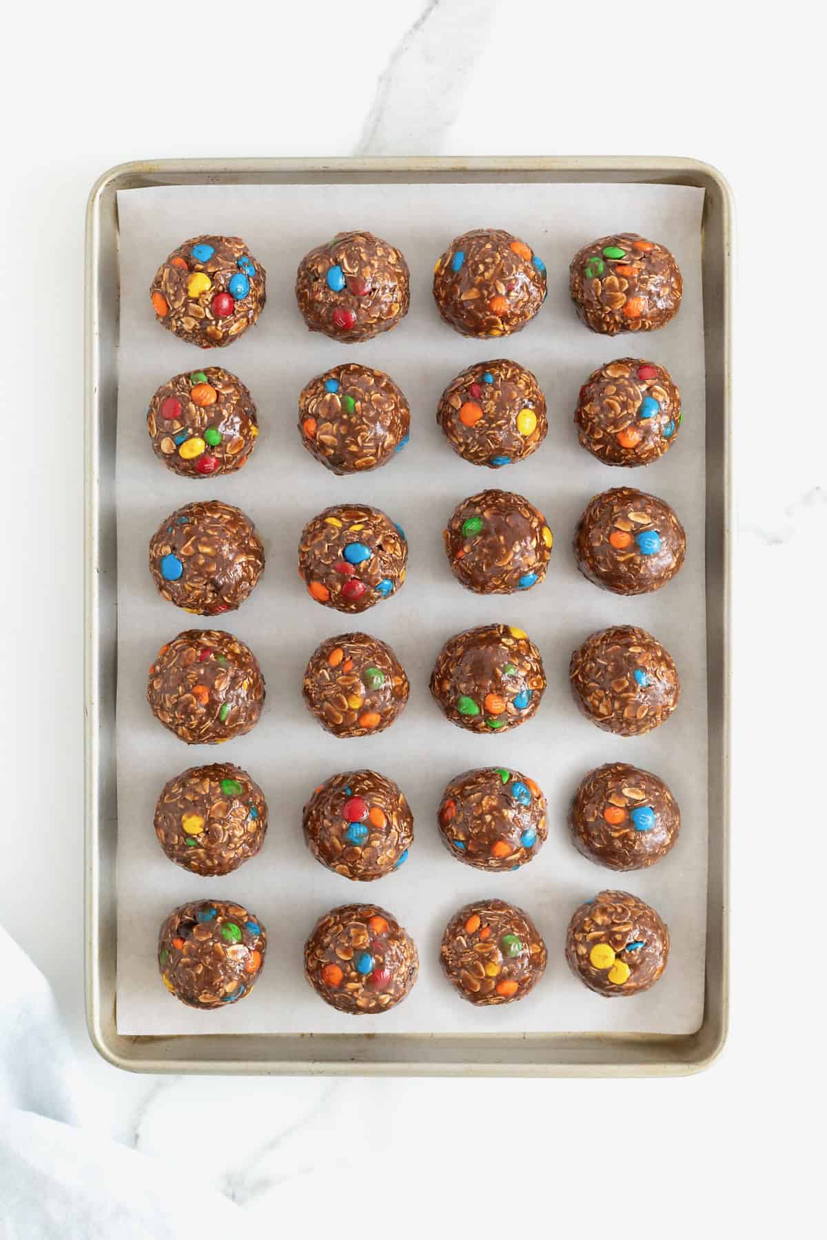 M&M Nutella Oatmeal balls on a parchment lined baking sheet.