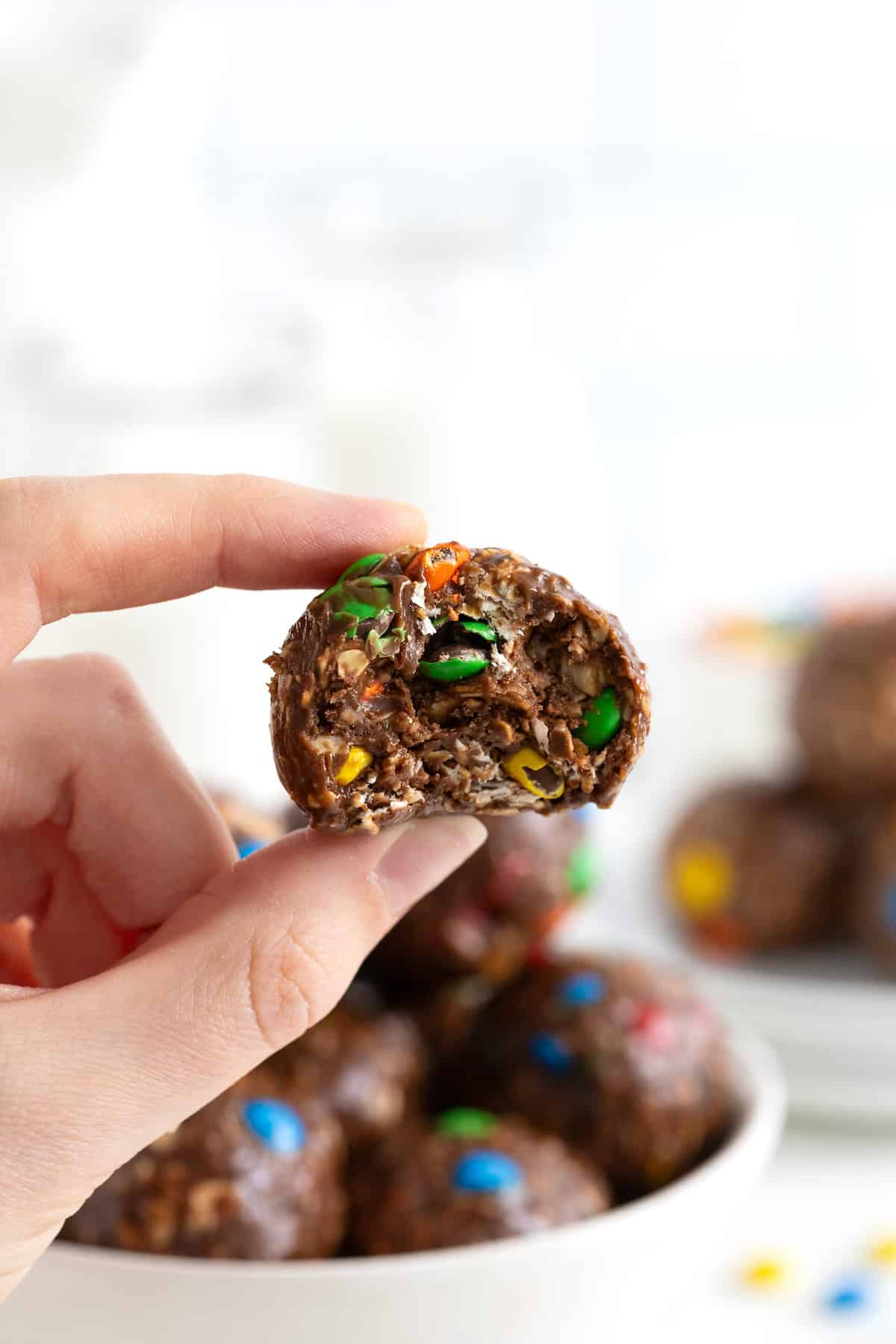 A hand holding a Nutella M&M ball between the thumb and forefinger.