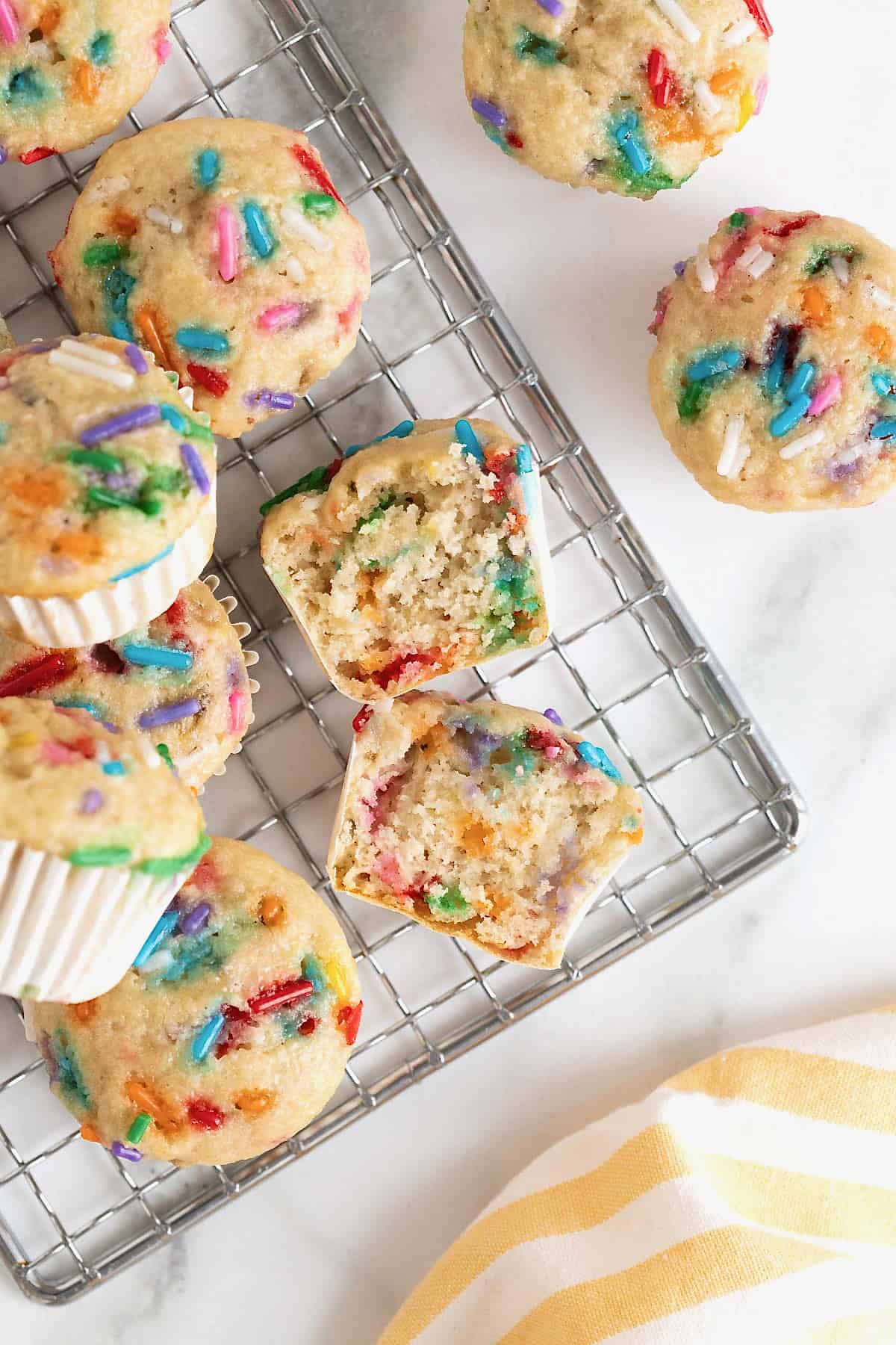 Confetti mini muffins on a metal cooling rack.
