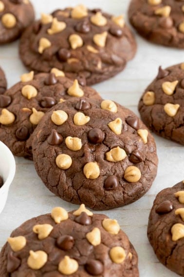 Nine chocolate peanut butter chip cookies on a white surface.
