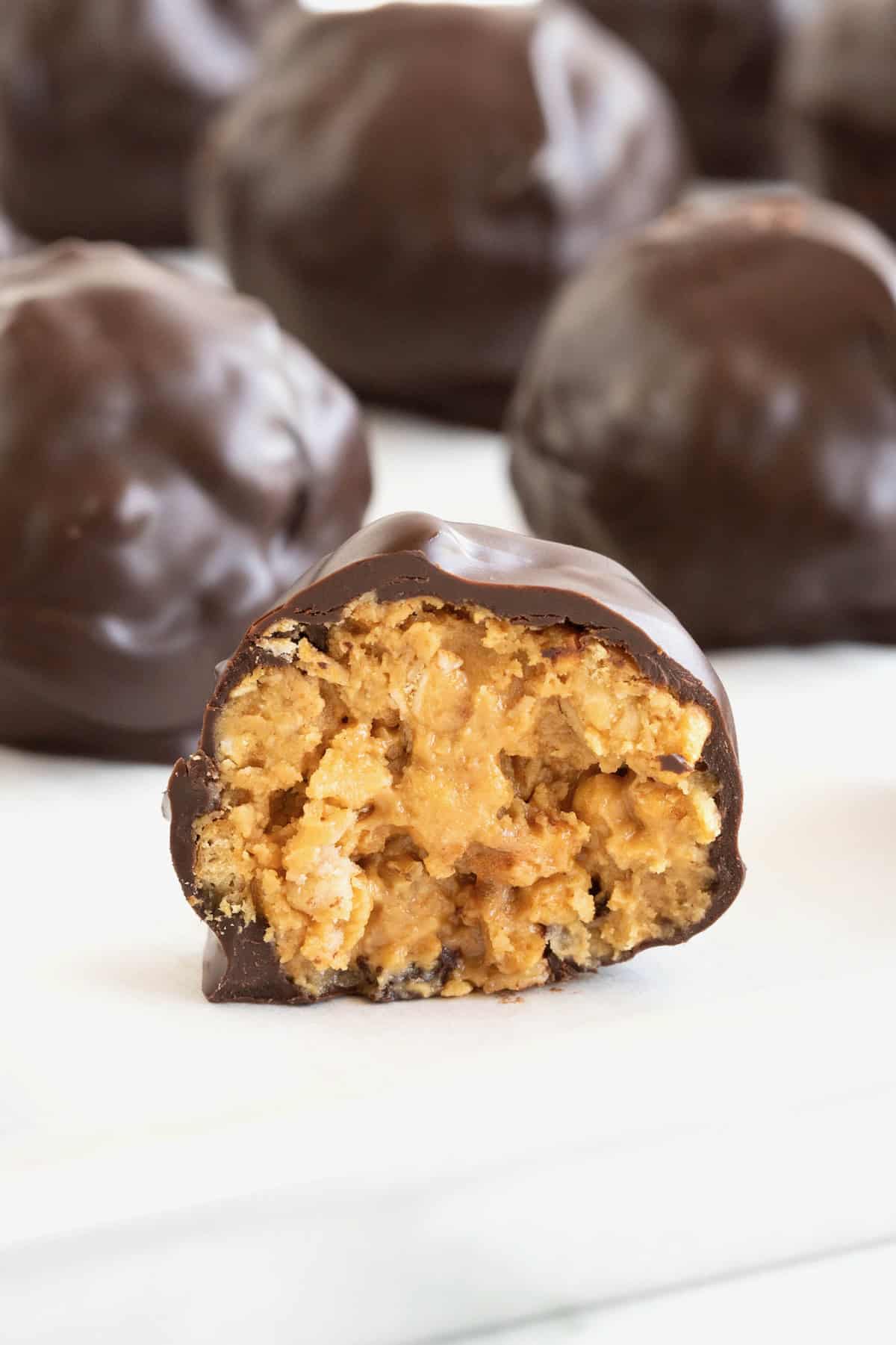 A dark chocolate covered peanut butter ball cut in half on a piece of parchment.