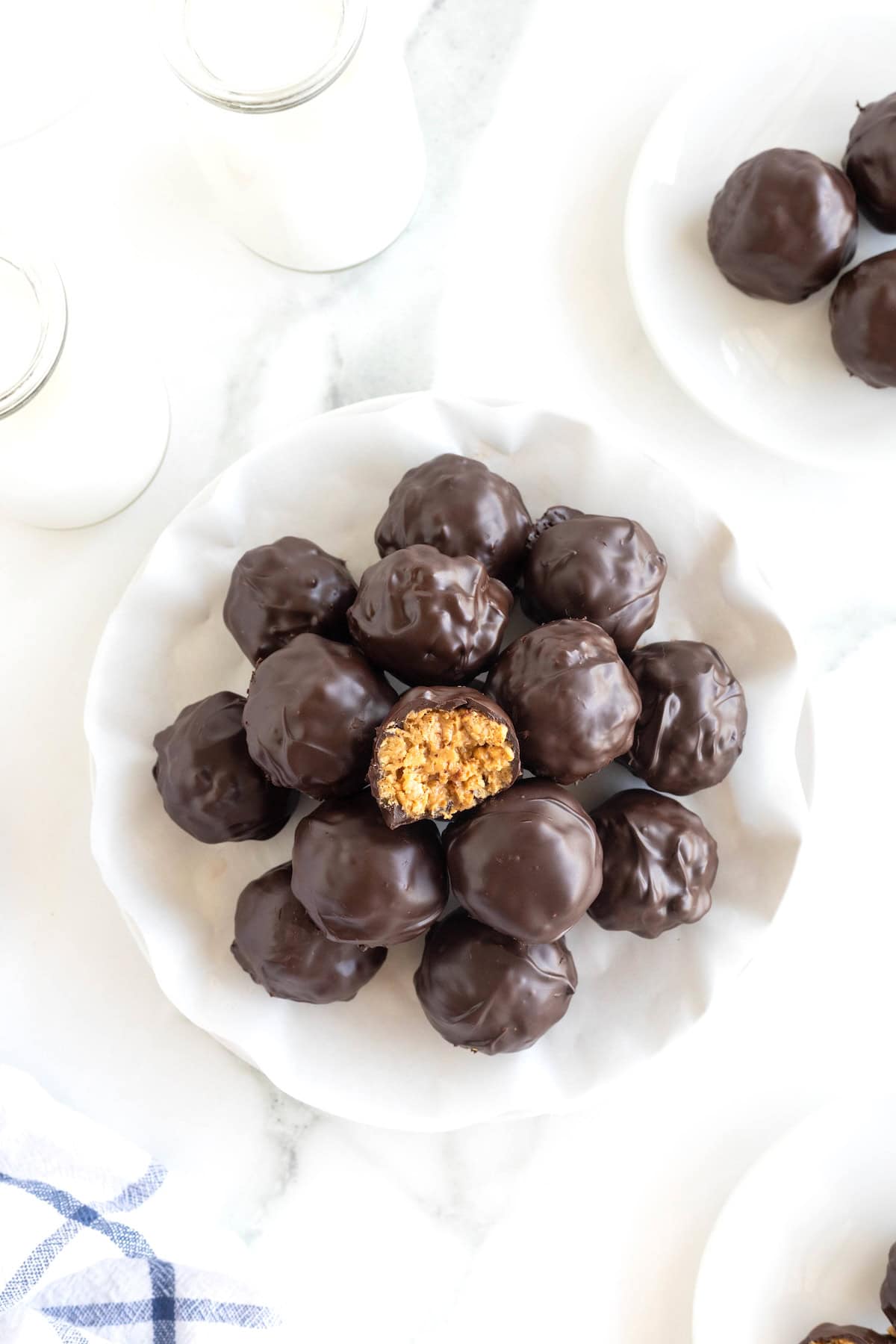 A pile of dark chocolate peanut butter balls in a parchment lined white serving dish.