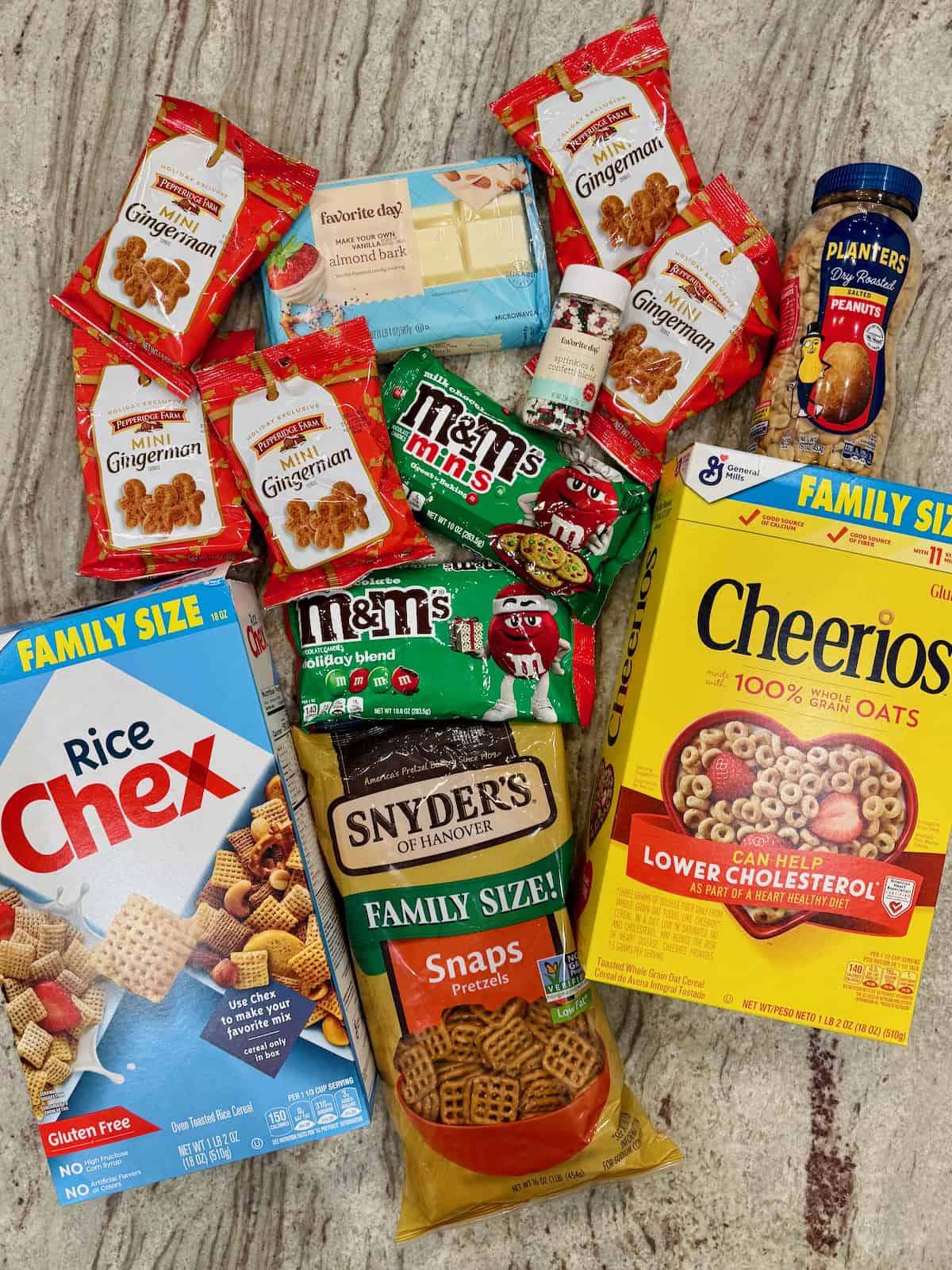 Ingredients to make Christmas Crunch Snack Mix on a gray marble counter.