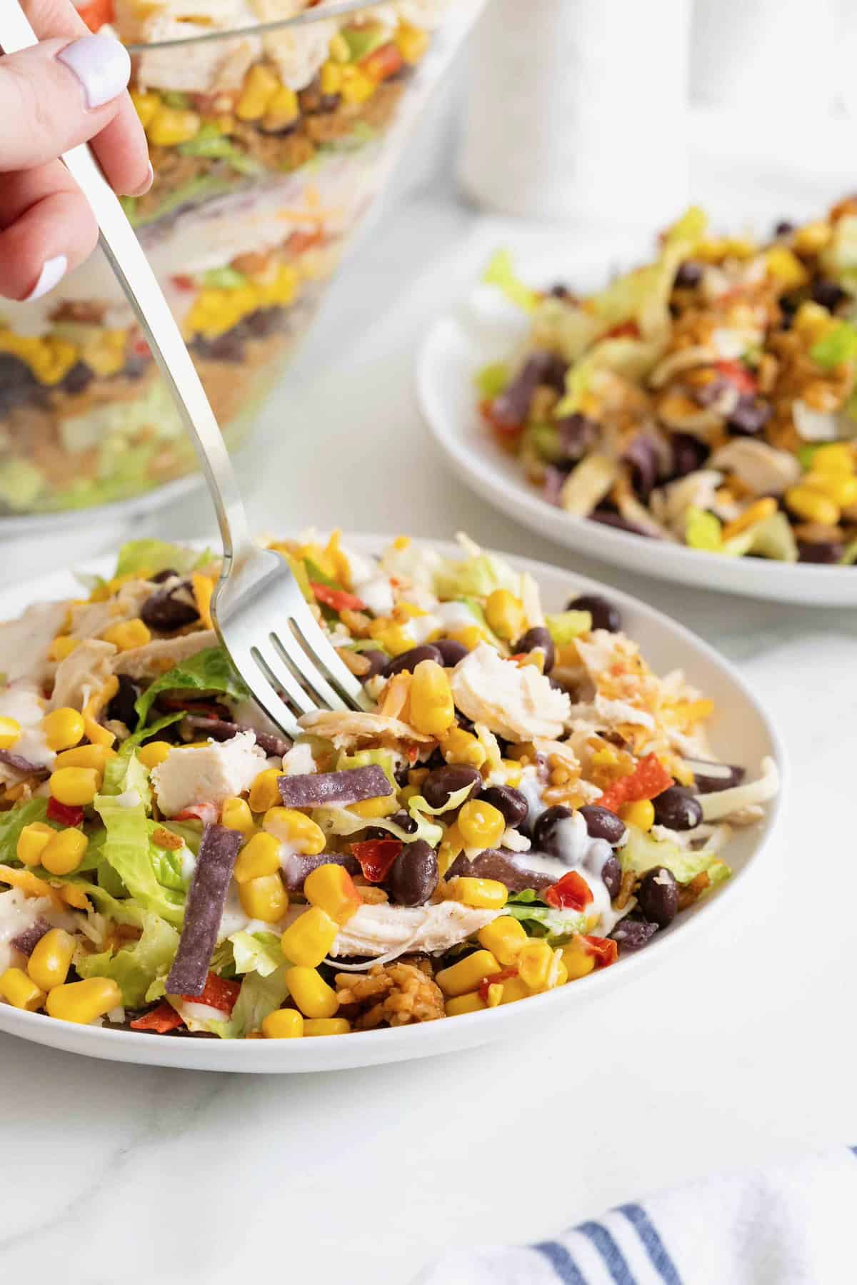 A bite being taken from a plate of chicken taco salad.