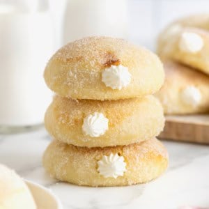 A stack of three cream filled baked donuts on a white surface.