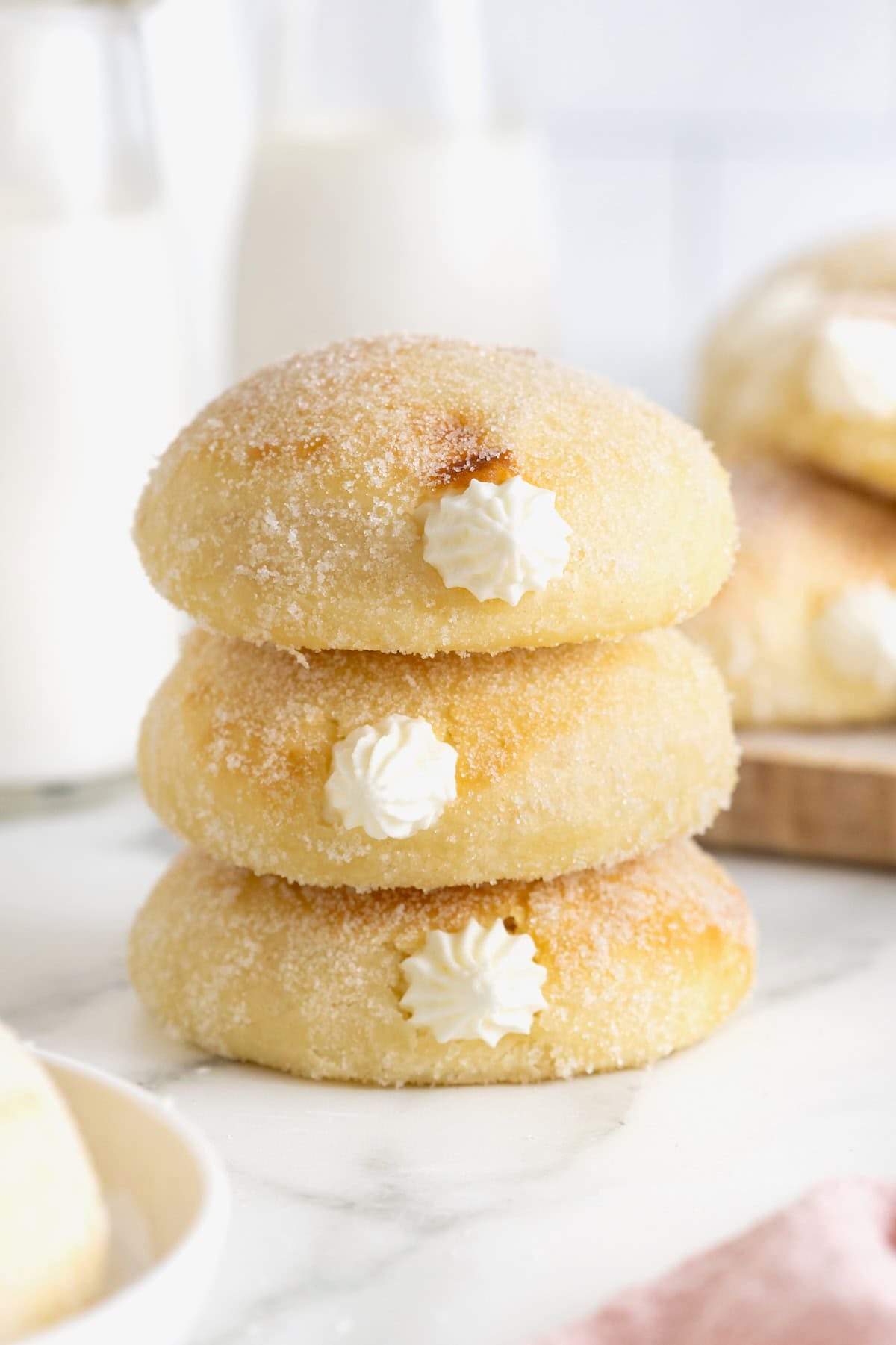 A stack of three cream filled baked donuts on a white surface.