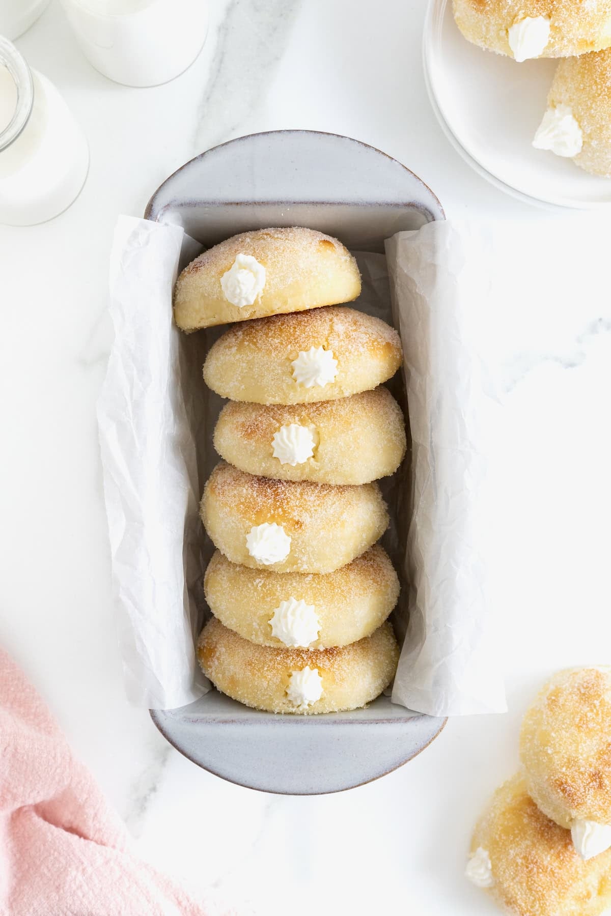 Six cream filled baked donuts in a parchment lined loaf pan.