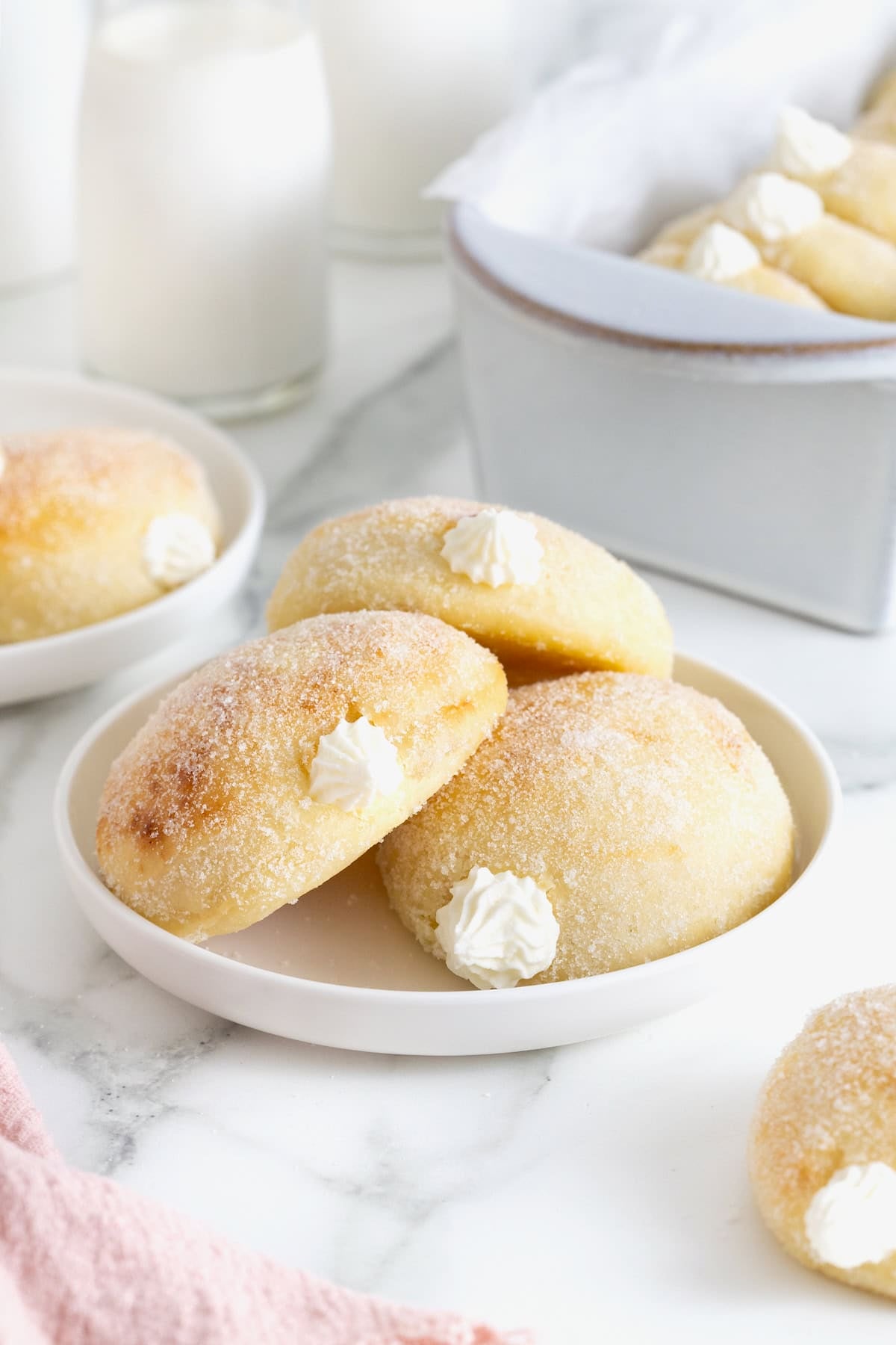 Three cream filled donuts on a white rimmed plate.