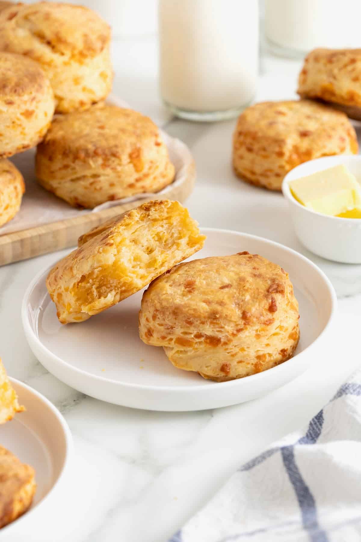 Two cheddar biscuits on a white rimmed plate.