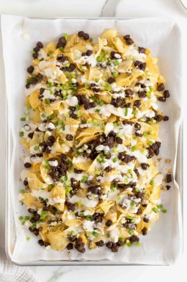 Steak and Blue Cheese Nachos on a parchment lined baking sheet.