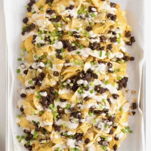 Steak and Blue Cheese Nachos on a parchment lined baking sheet.