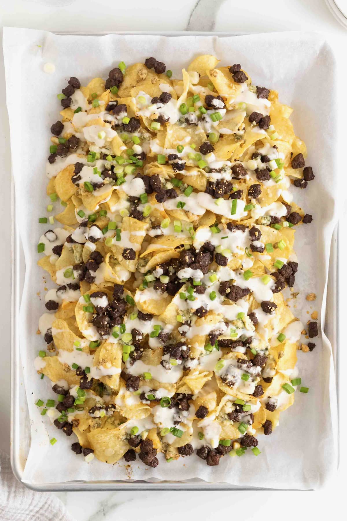 Steak and Blue Cheese Nachos on a parchment lined baking sheet.