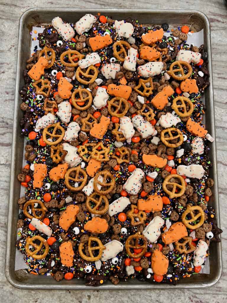 A pile of Halloween snack mix on a rimmed baking sheet.
