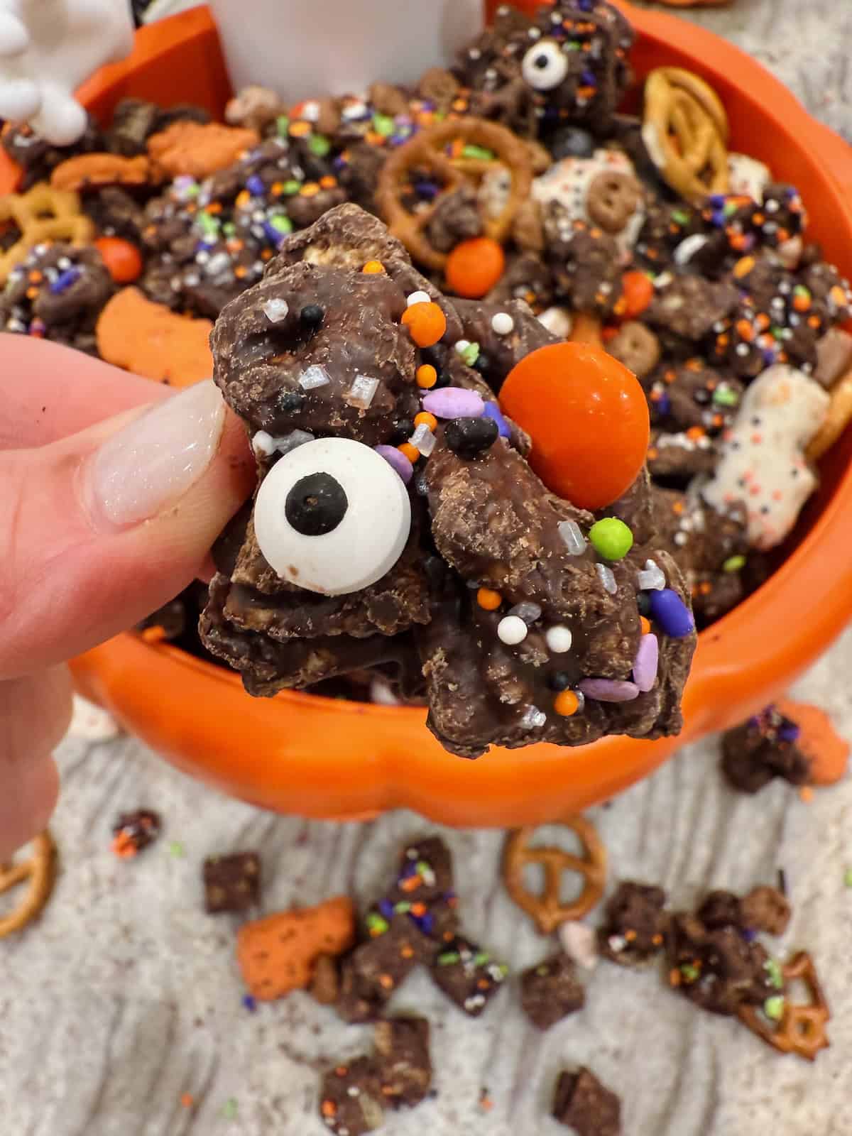 A chunk of Halloween Snack Mix between two fingers.