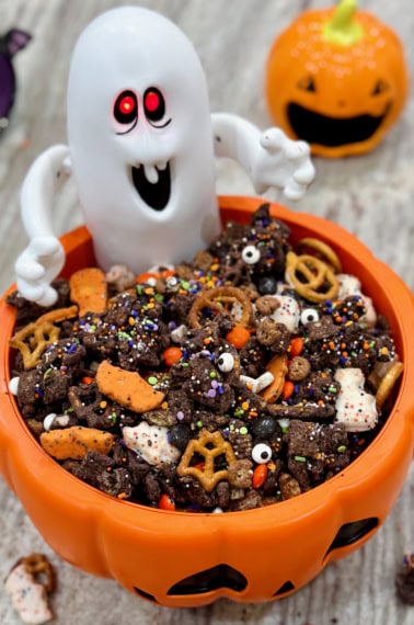 Halloween snack mix in a festive orange jack-o-lantern bowl with a ghost figure.