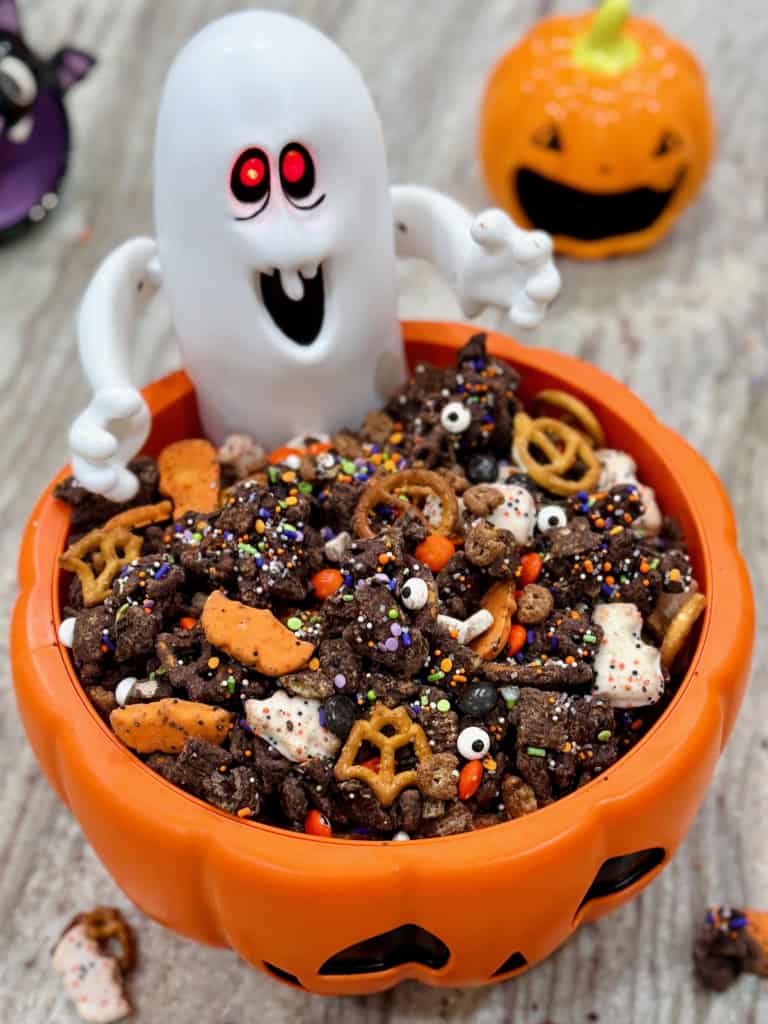 Halloween snack mix in a festive orange jack-o-lantern bowl with a ghost figure.