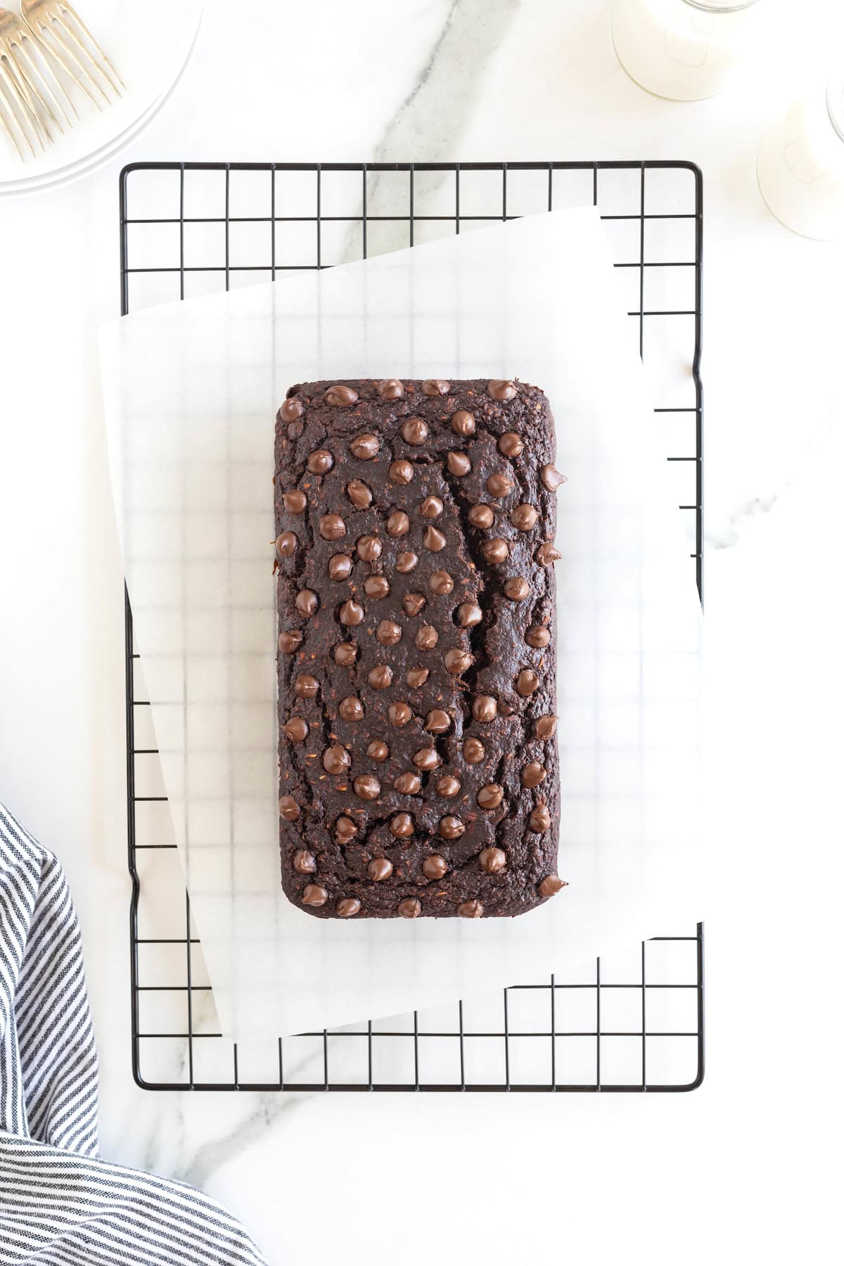 A loaf of chocolate banana bread on a parchment lined wire cooling rack.