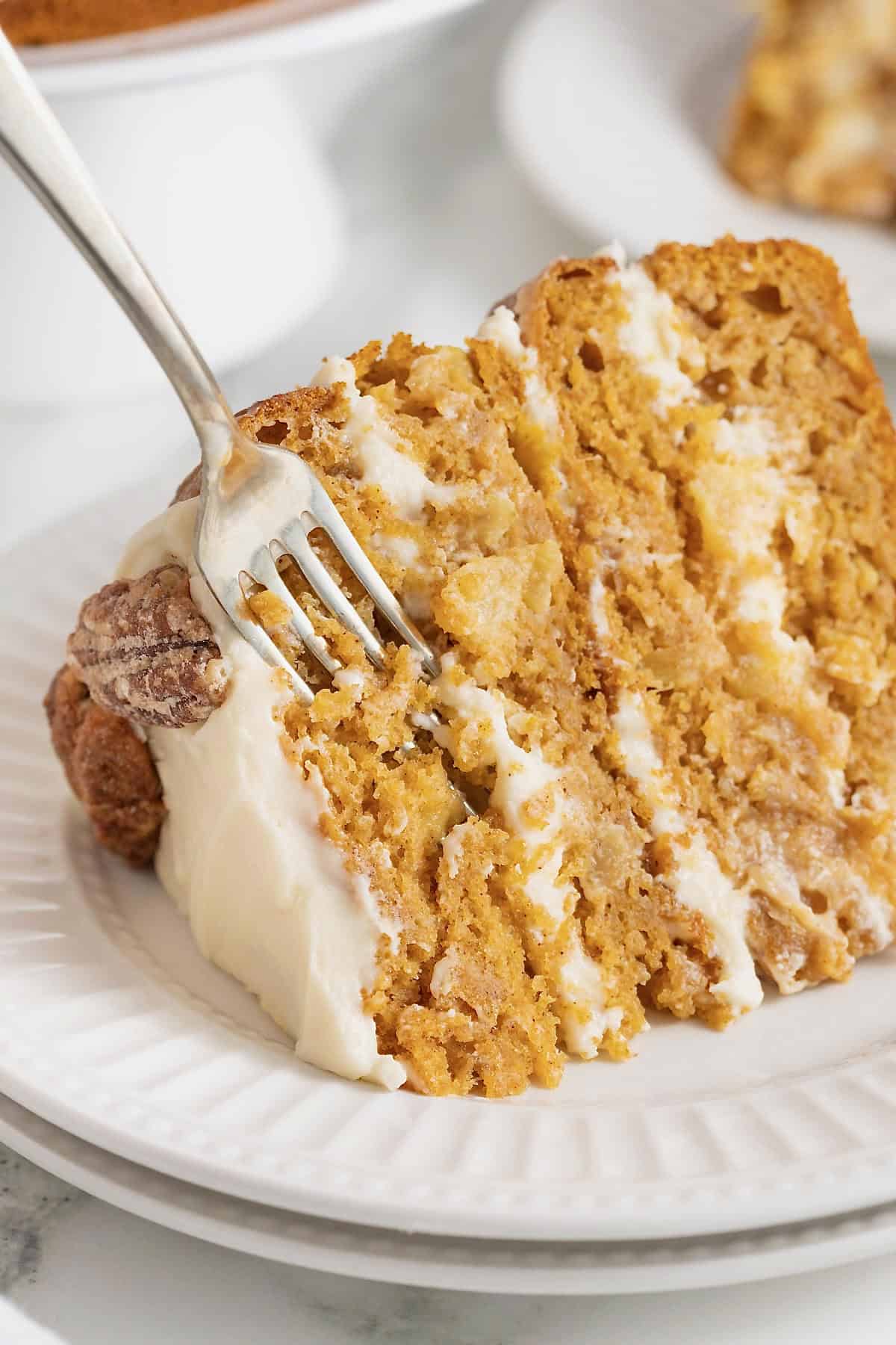 A for sticking out of a piece of pumpkin pineapple cake on a white fluted plate/