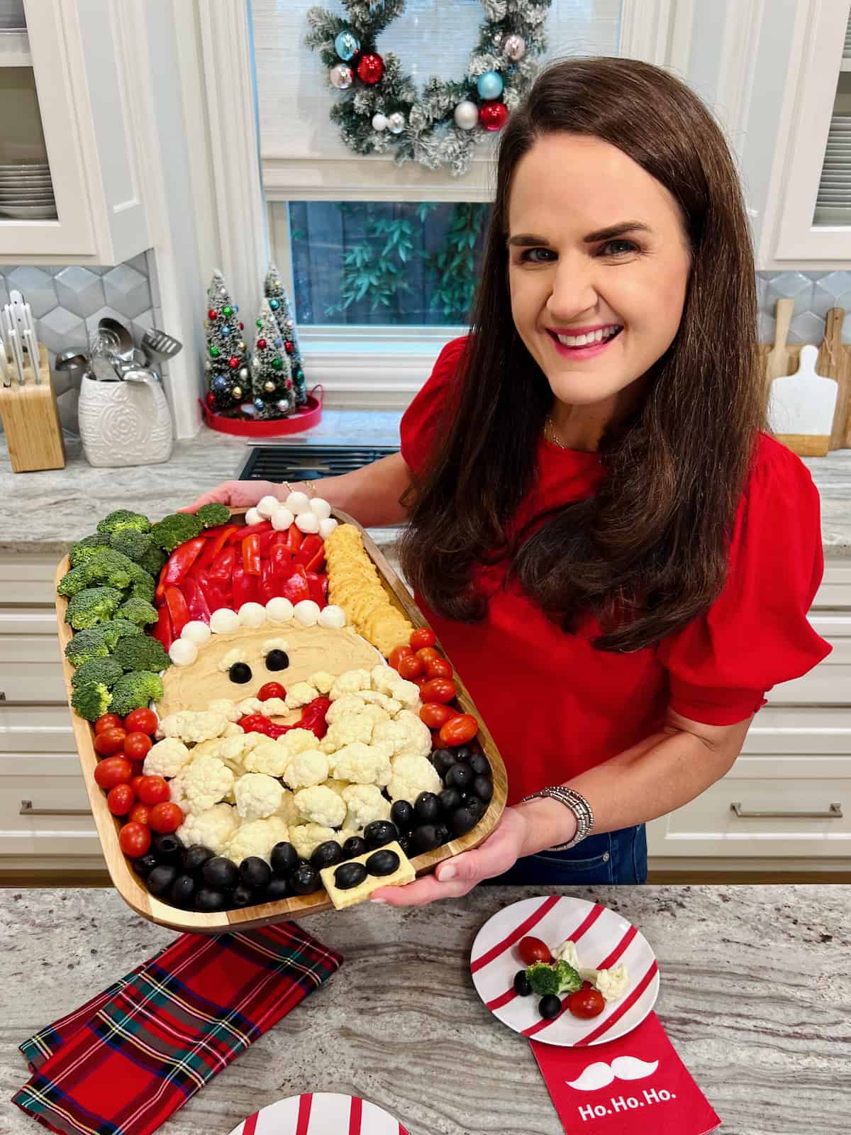 Maegan Brown wearing a bright red sweater holding a Santa Snack Board.