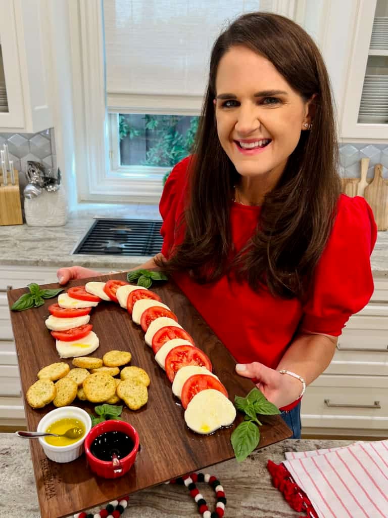 Maegan Brown holding her original candy cane caprese on a dark wood board.