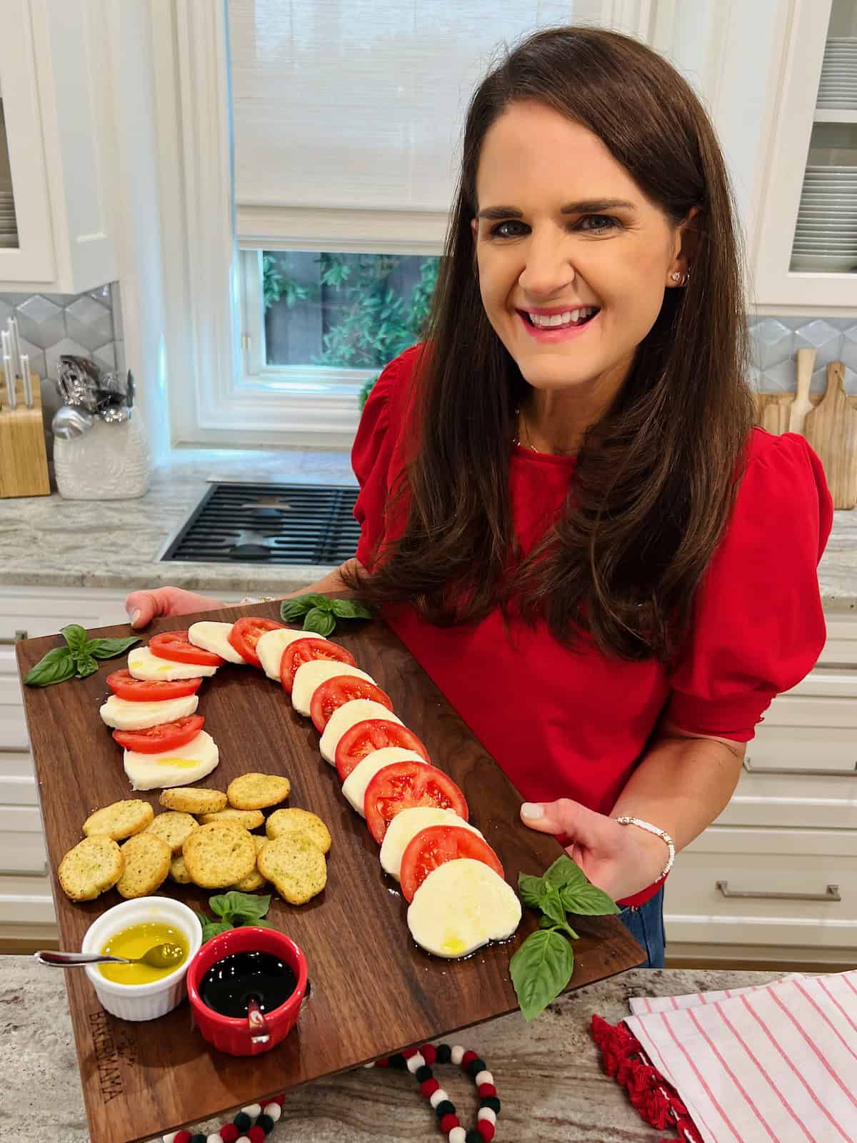 Maegan Brown holding her original candy cane caprese on a dark wood board.