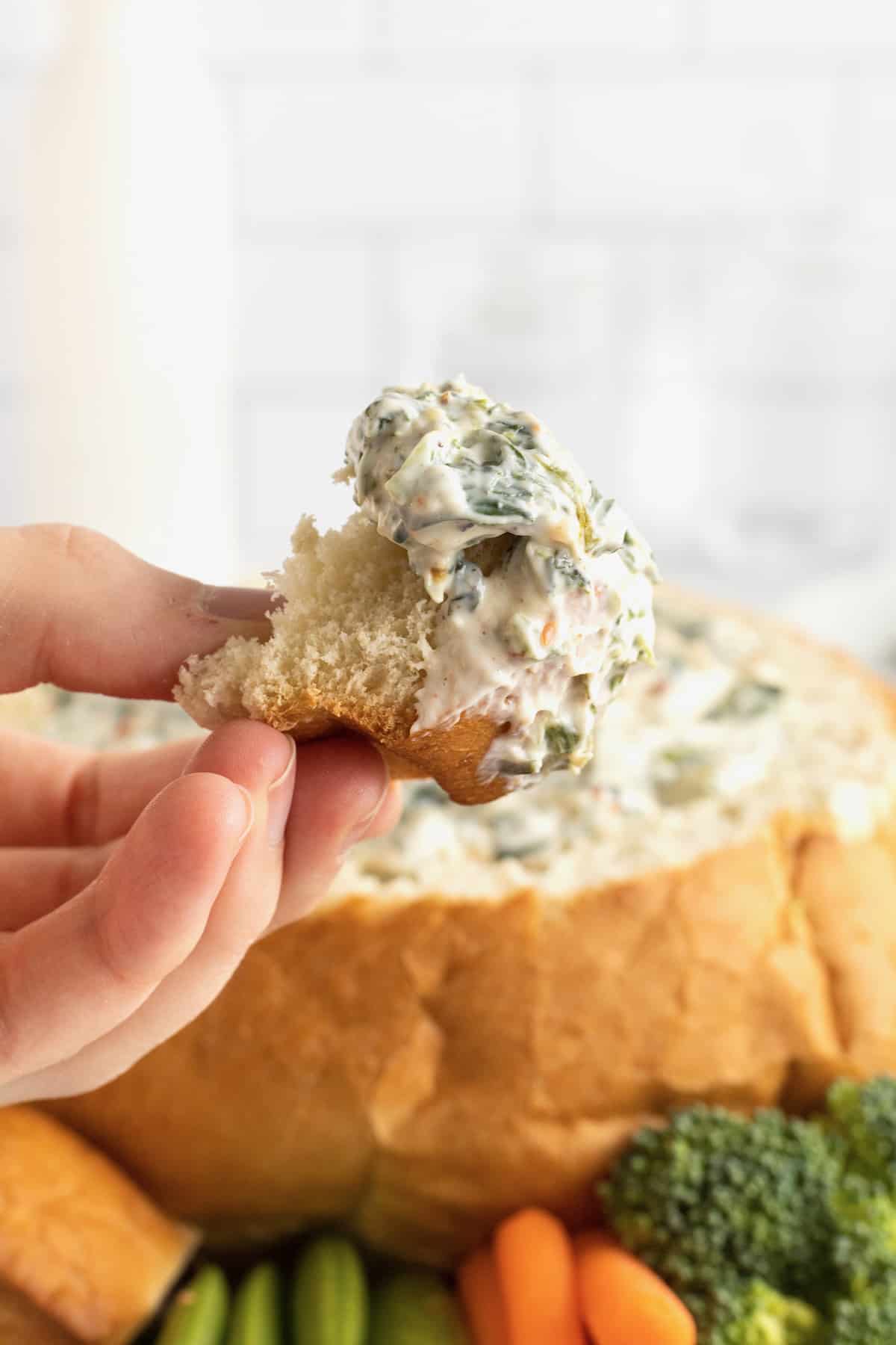 A bite of creamy spinach dip on a bread chunk.