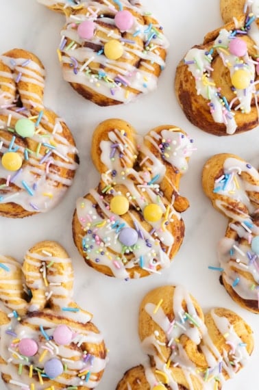 Seven Easter bunny cinnamon rolls on a white marble counter.