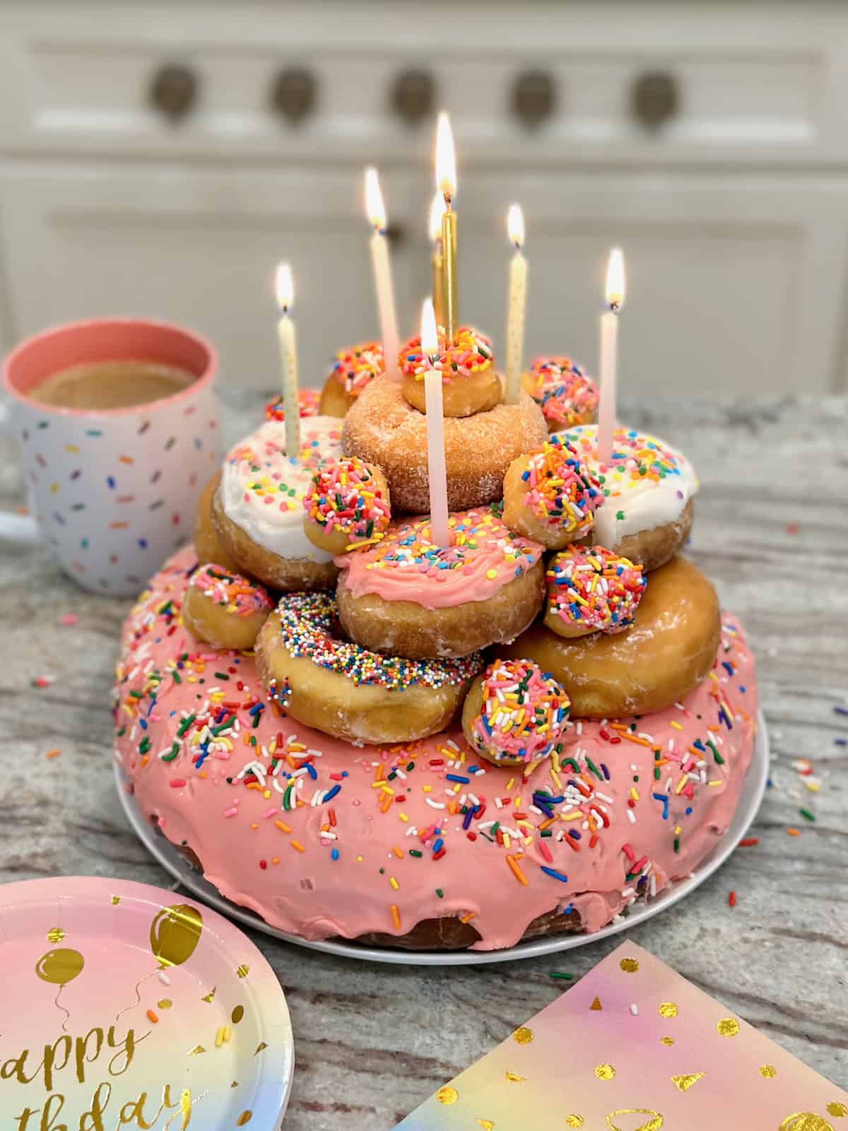 A birthday cake made out of frosted donuts with six candles in it. 