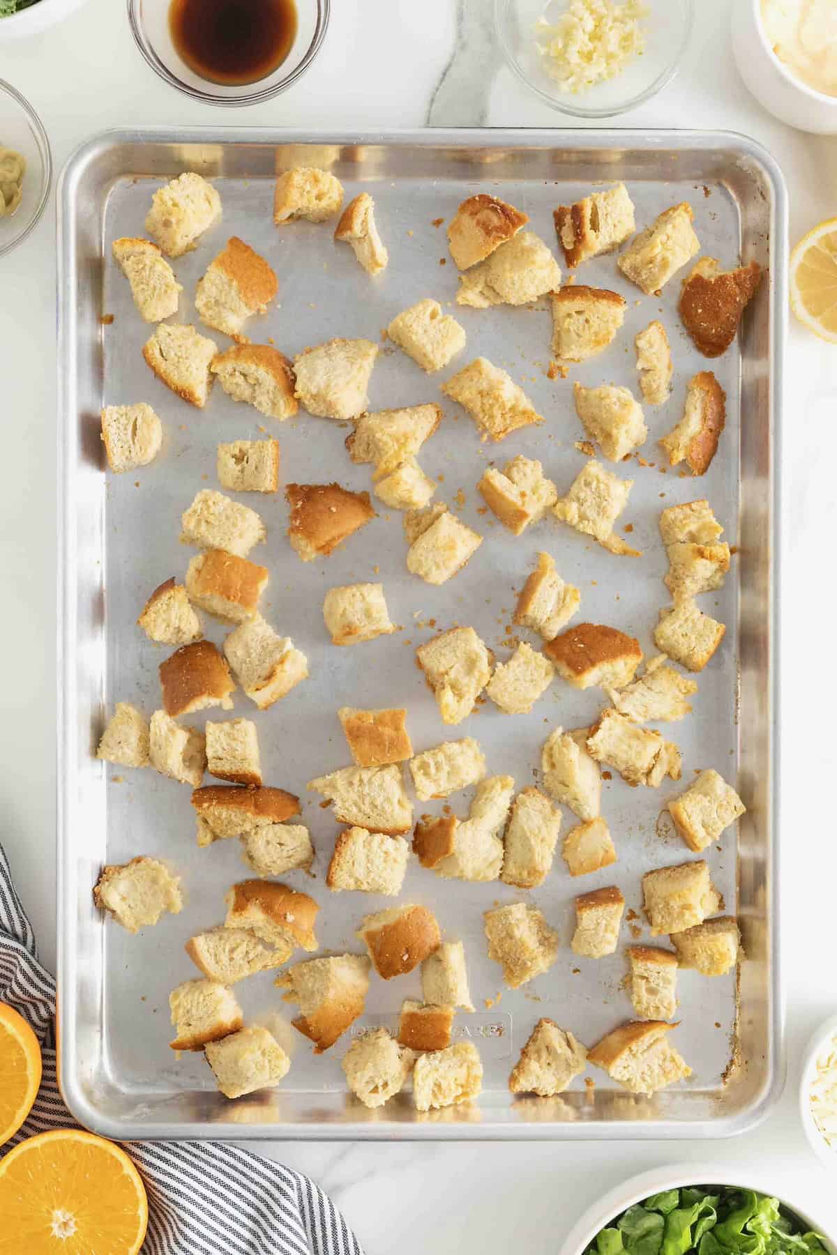 Baked croutons on an aluminum baking sheet.