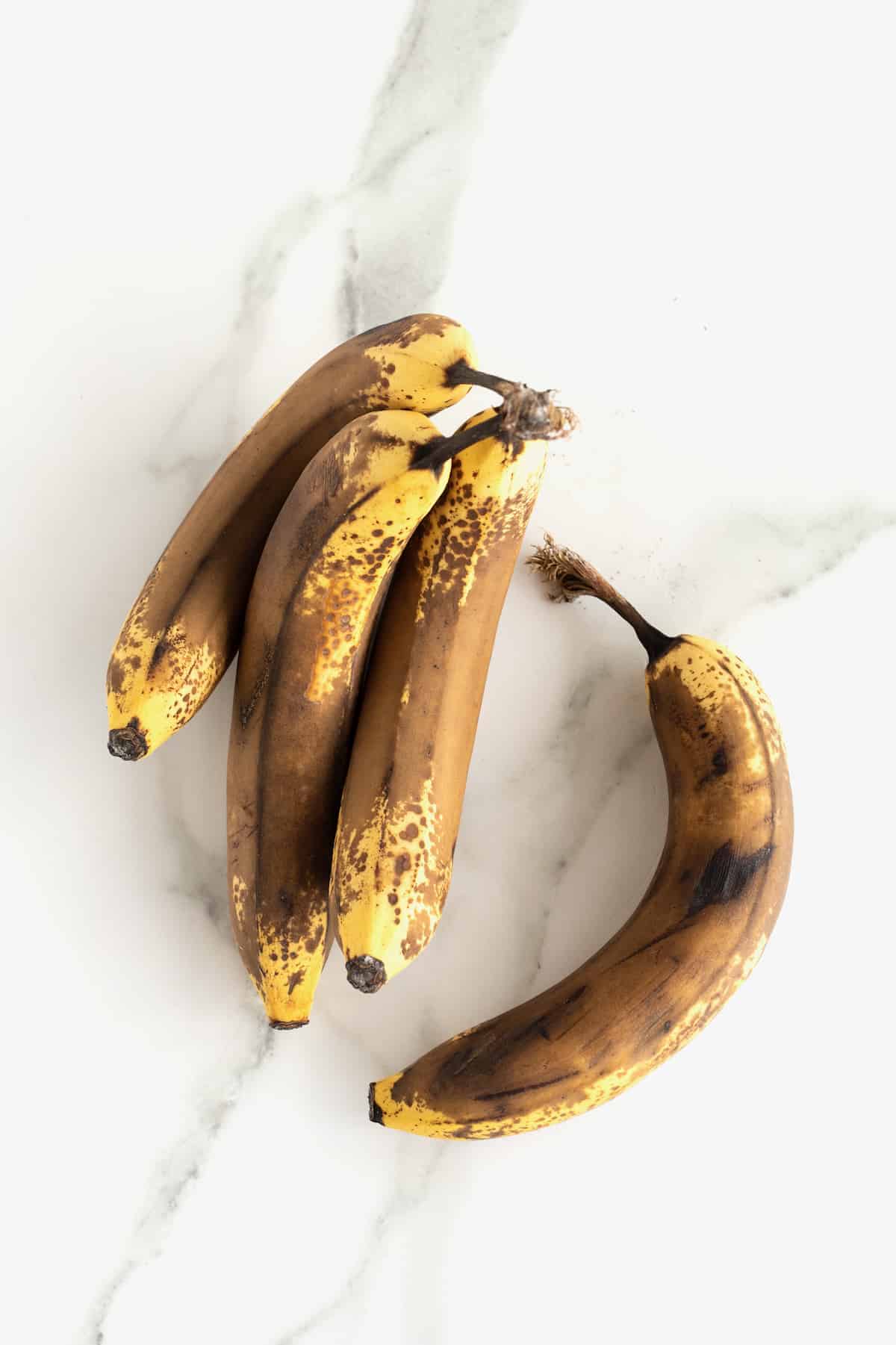 Brown bananas on a white marble counter.