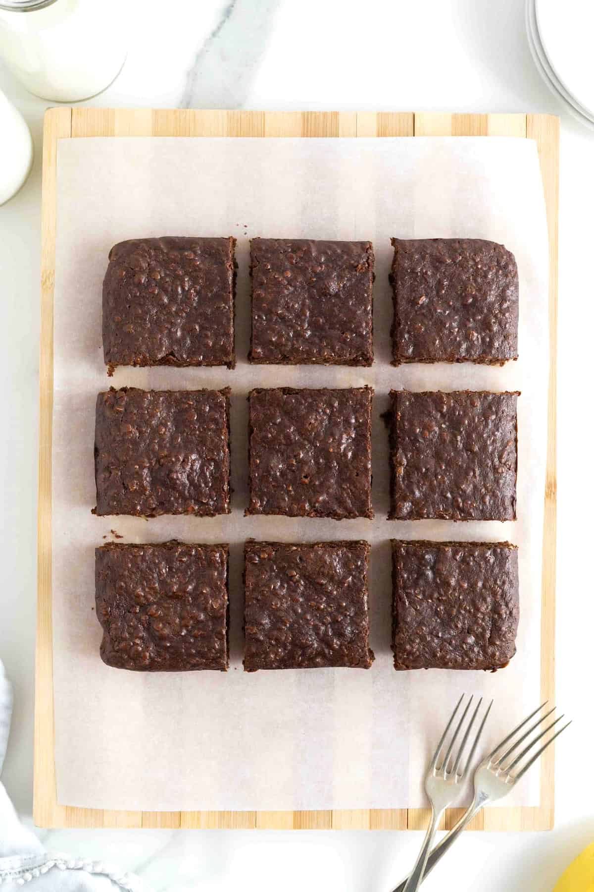 Nine breakfast brownies on a parchment lined wooden cutting board.