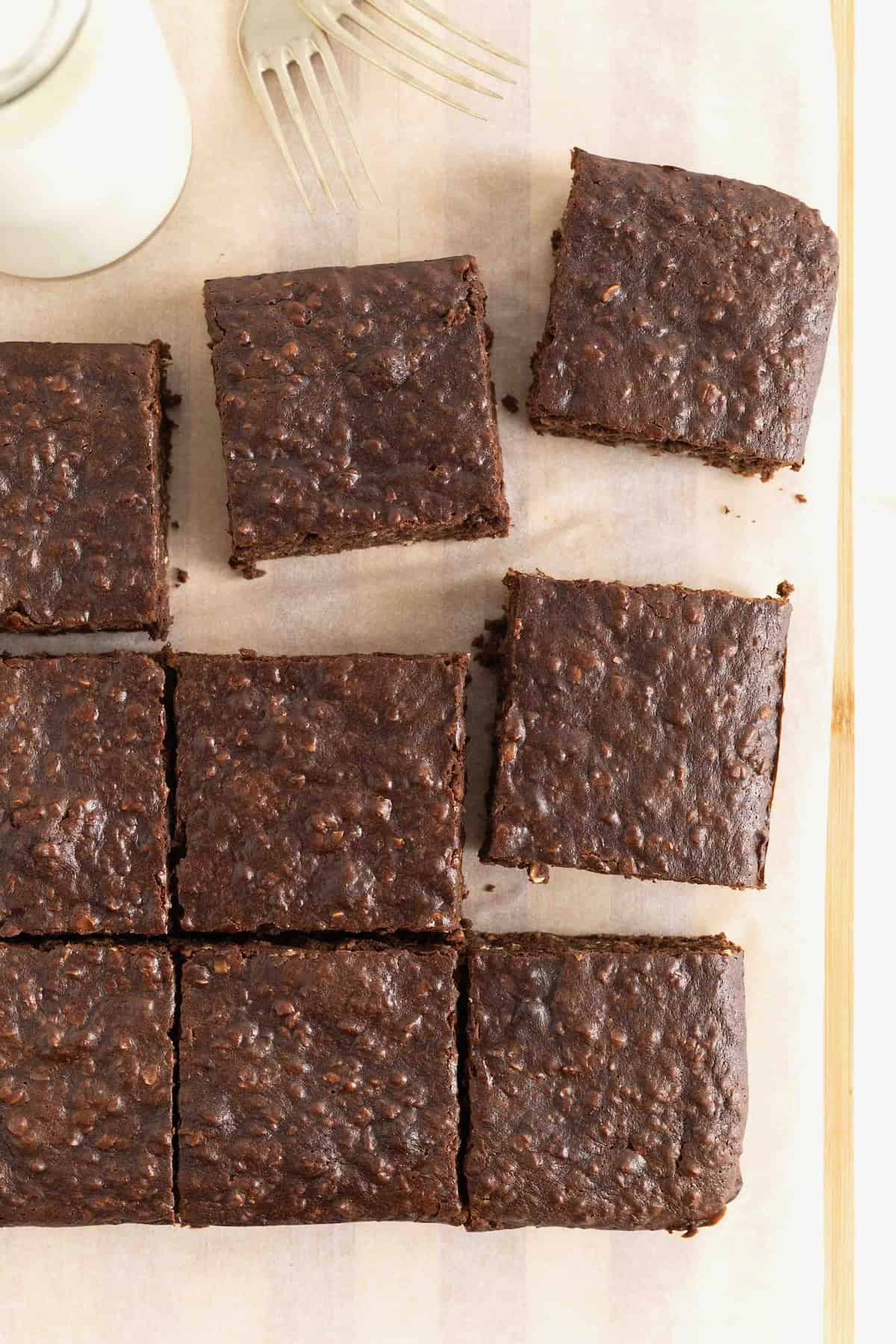 Nine breakfast brownies on a parchment lined wooden cutting board.
