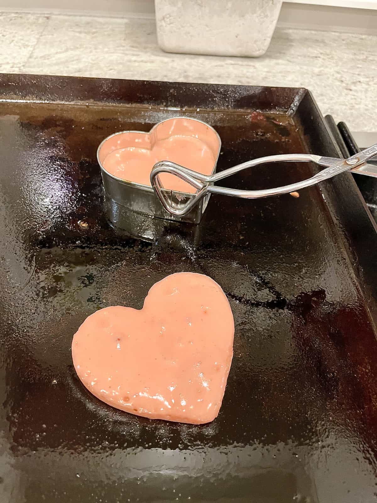 Remove cookie cutters from pancakes with tongs