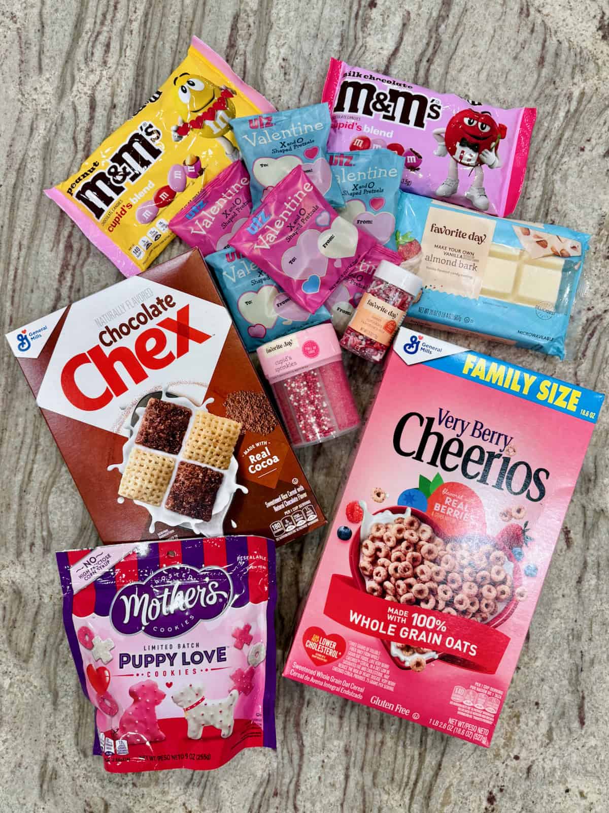 Ingredients to make XOXO Valentine's Snack Mix on a gray marble counter.