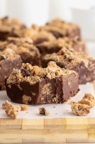 Several pieces of chocolate chip cookie fudge on a parchment lined surface.