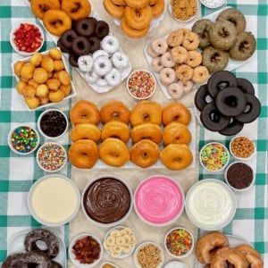 A variety of donuts, frosting, sprinkles and decorations.