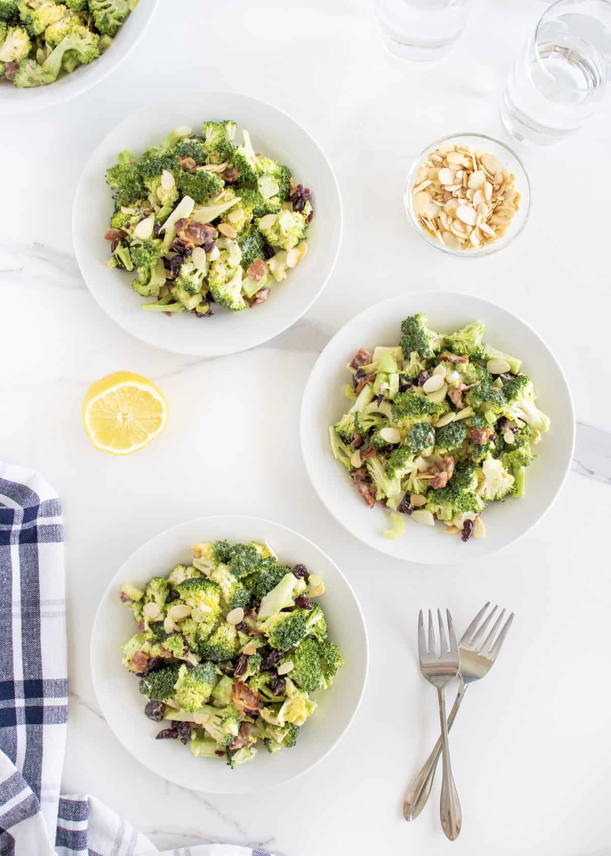 Three white salad plates with broccoli salad on them. 