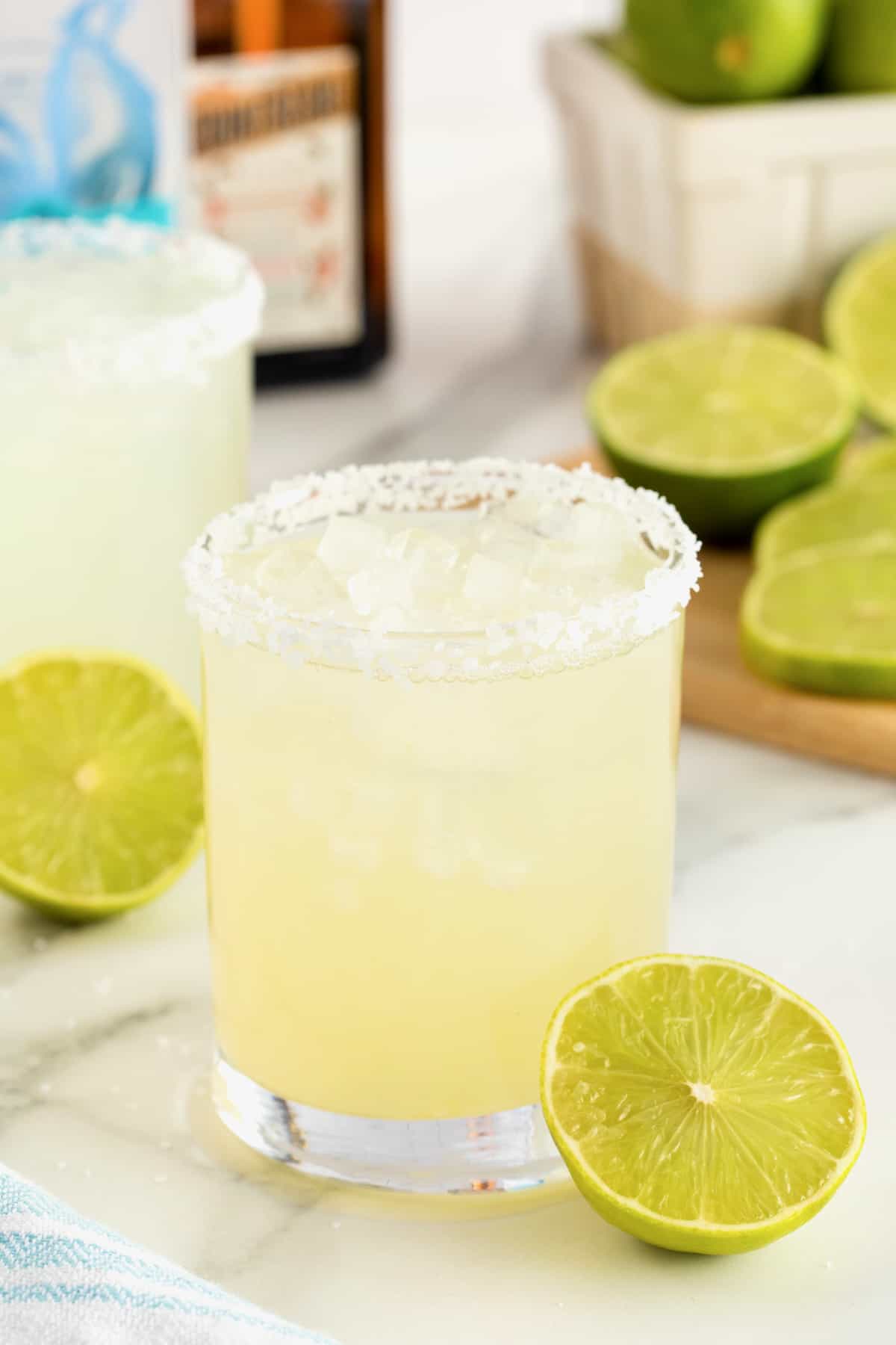 A salt rimmed glass filled with margarita on a white marble counter.