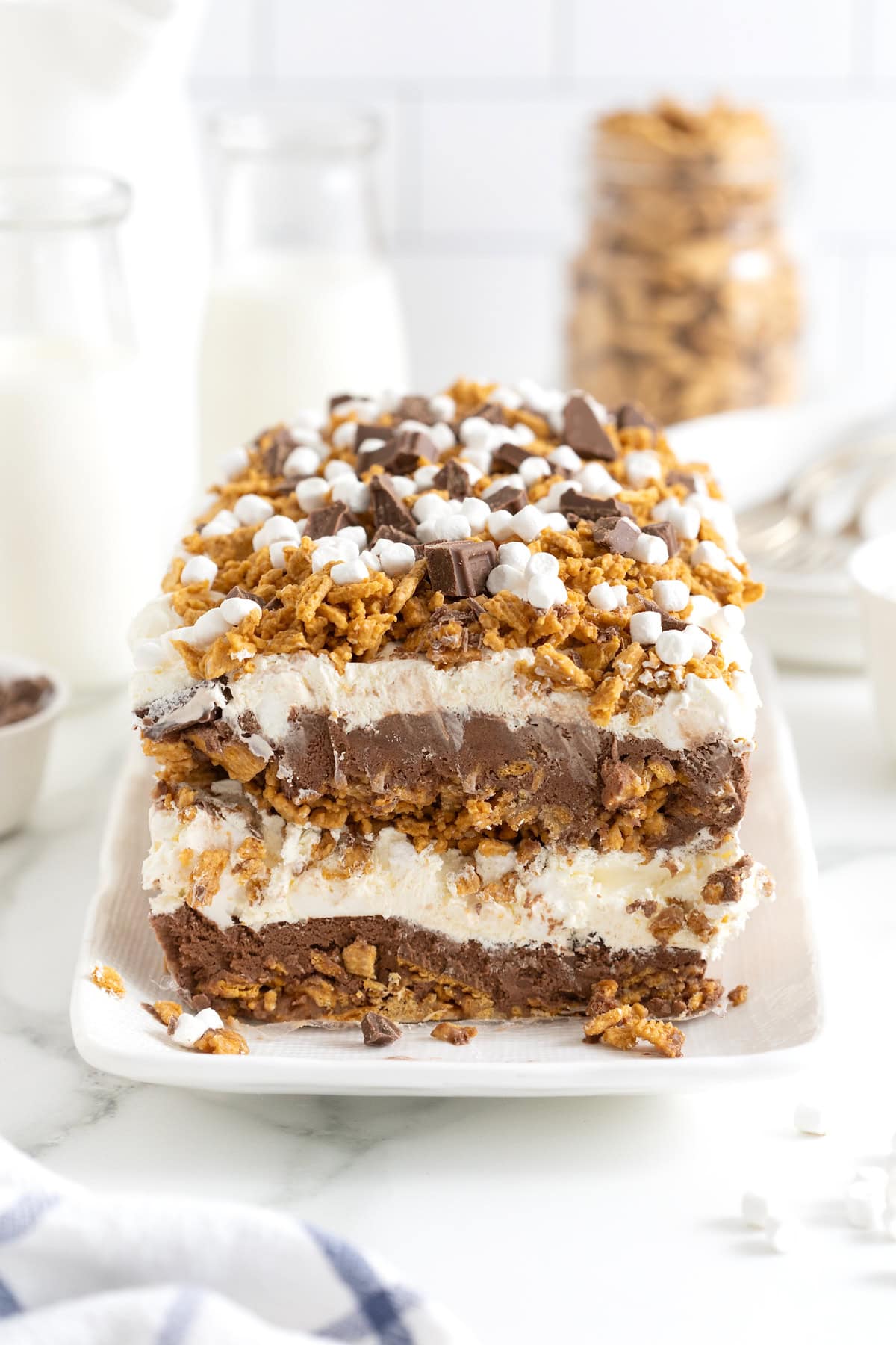 A layered s'mores ice cream cake topped with marshmallow bits, chocolate chunks and graham cracker crumbs.