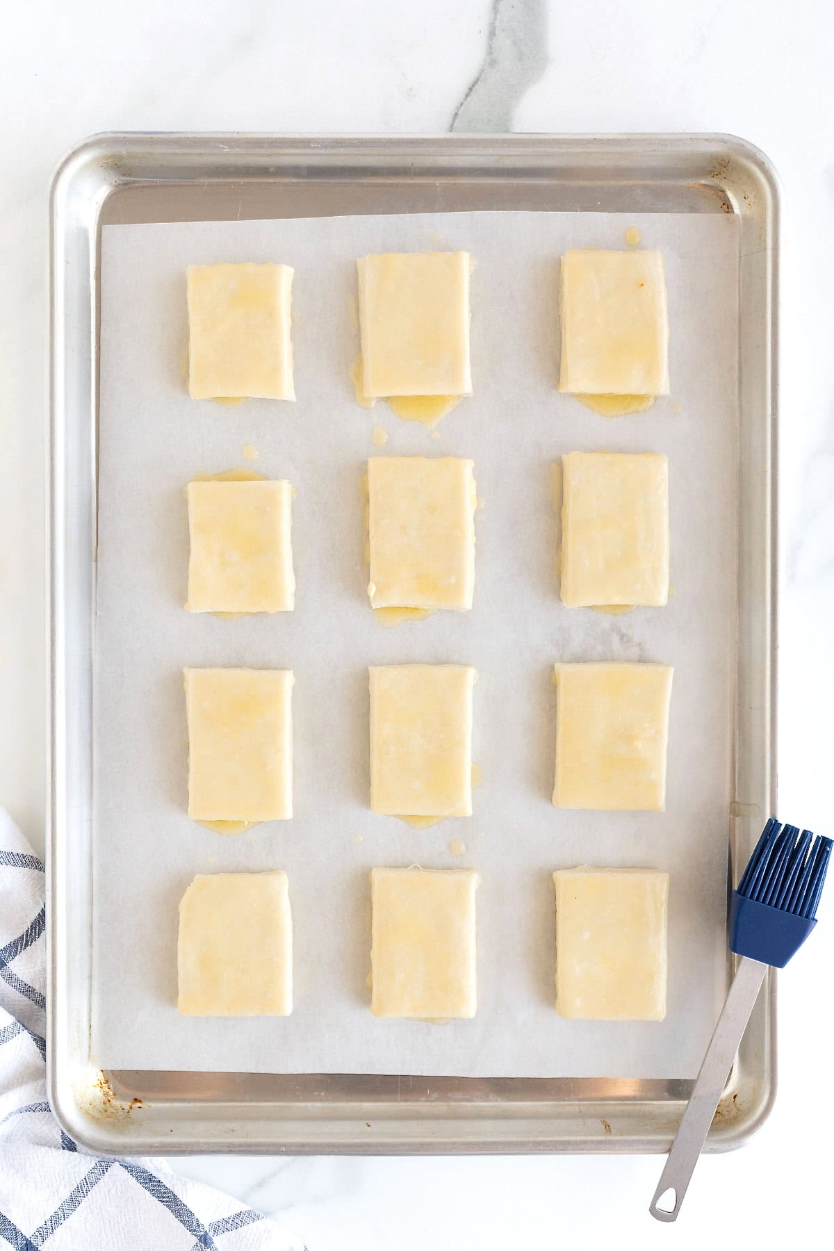 Butter milk biscuit dough in 12 squares on a parchment lined baking sheet.