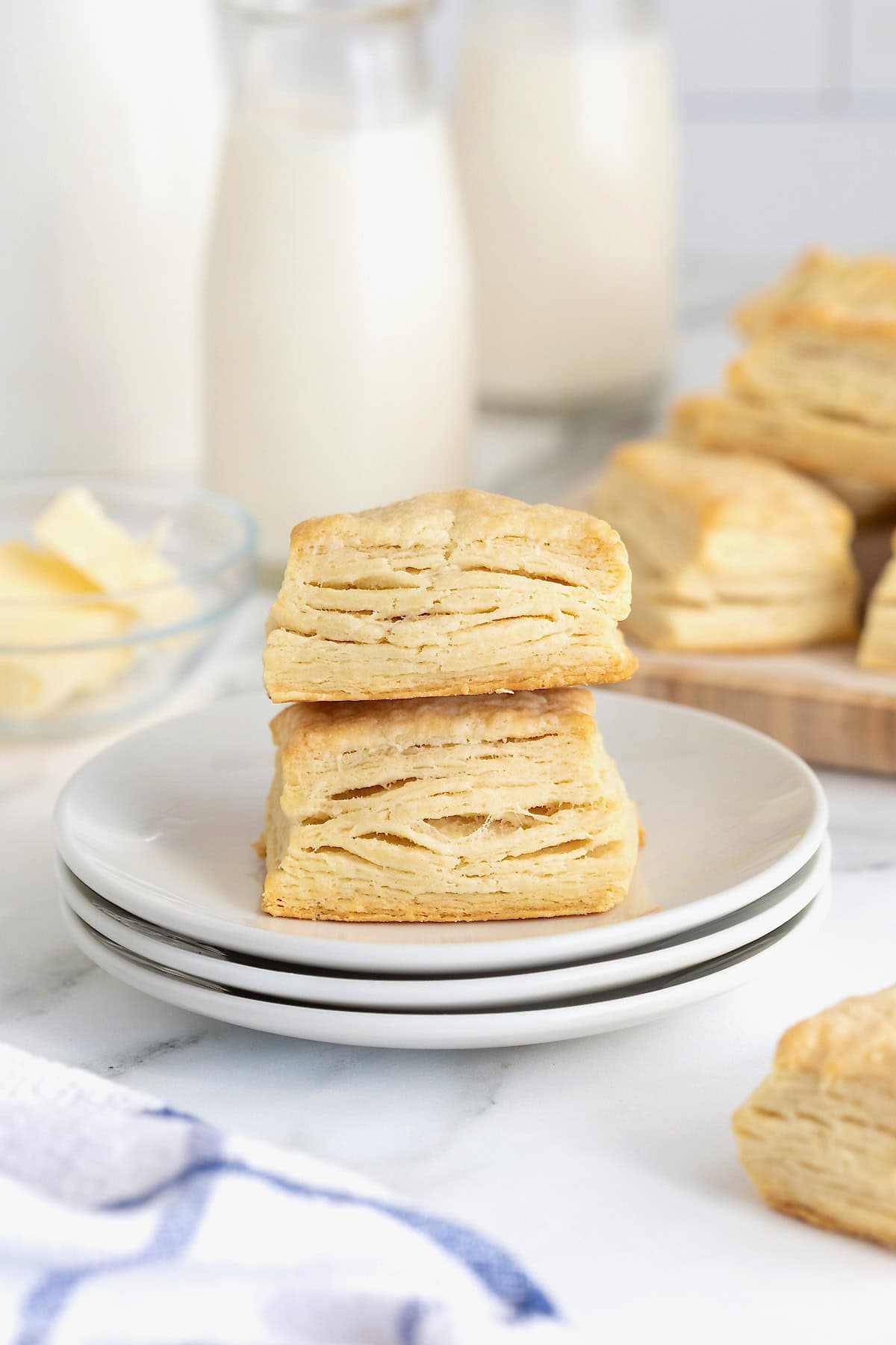 Two buttermilk biscuits stacked a white plate.