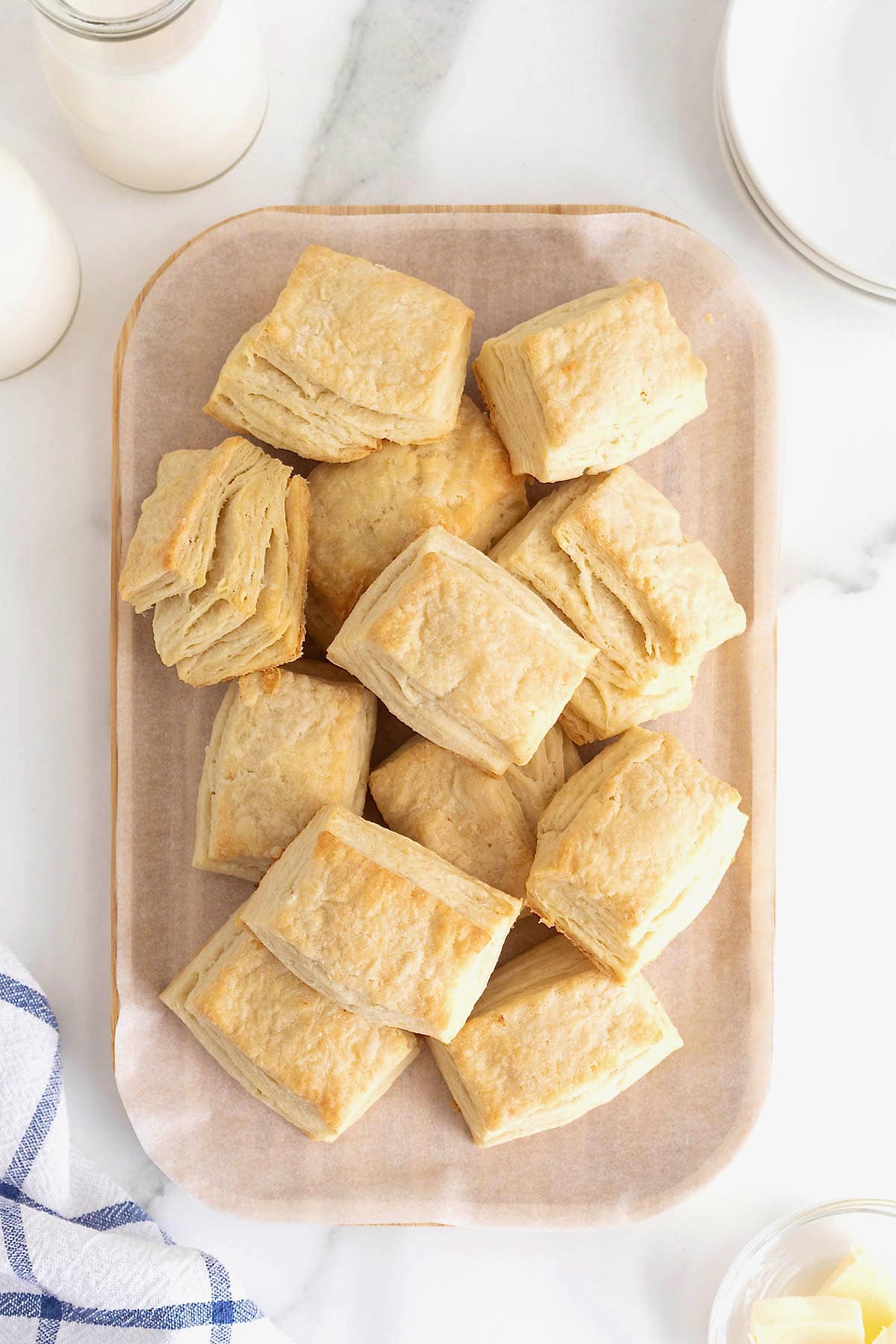 A pile of buttermilk biscuits on a wooden cutting board.