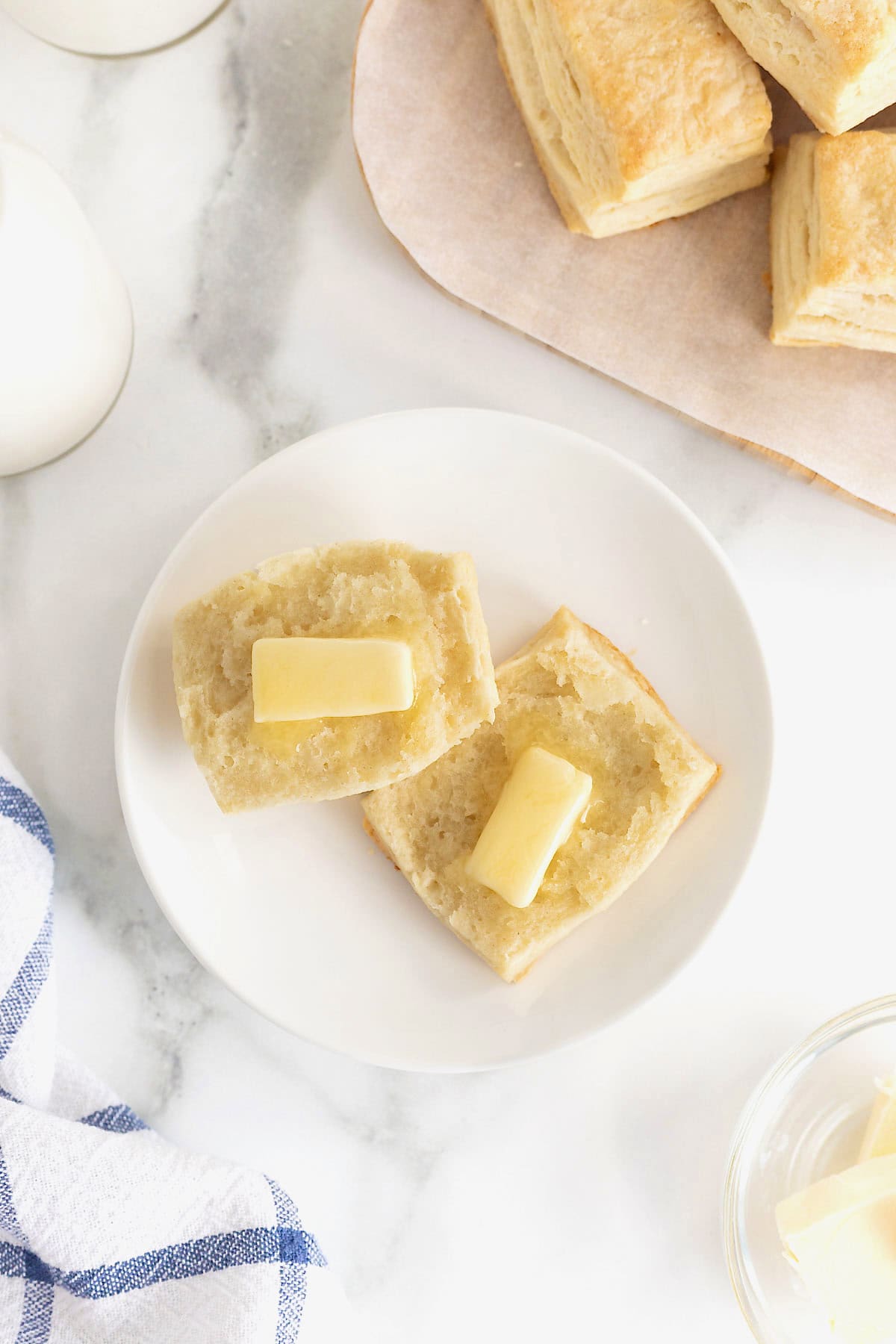 A biscuit cut in half with a pat of butter on each half.
