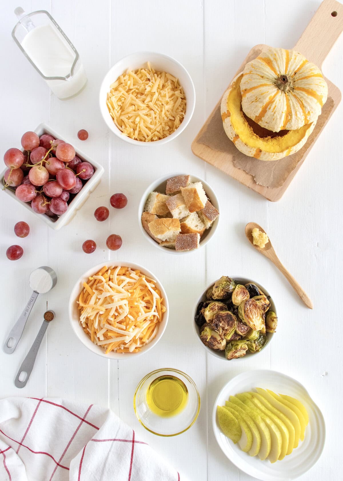 Ingredients to make gouda and cheddar cheese fondue on a white surface.