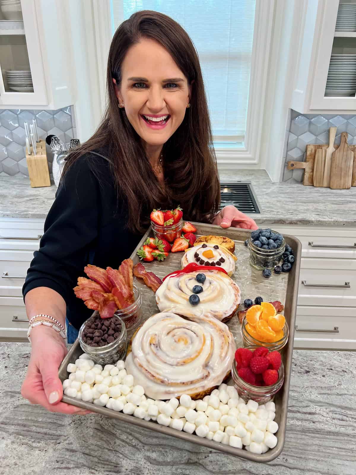 Maegan Brown wearing a black sweater holding a snowman breakfast tray.